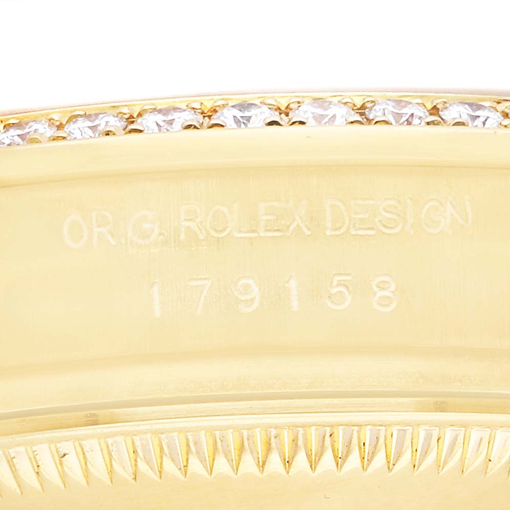 The image shows a close-up of the Rolex President 179158 Women
s Yellow Gold Mother of Pearl Dial model
s bezel edge with diamond accents and engraved markings.