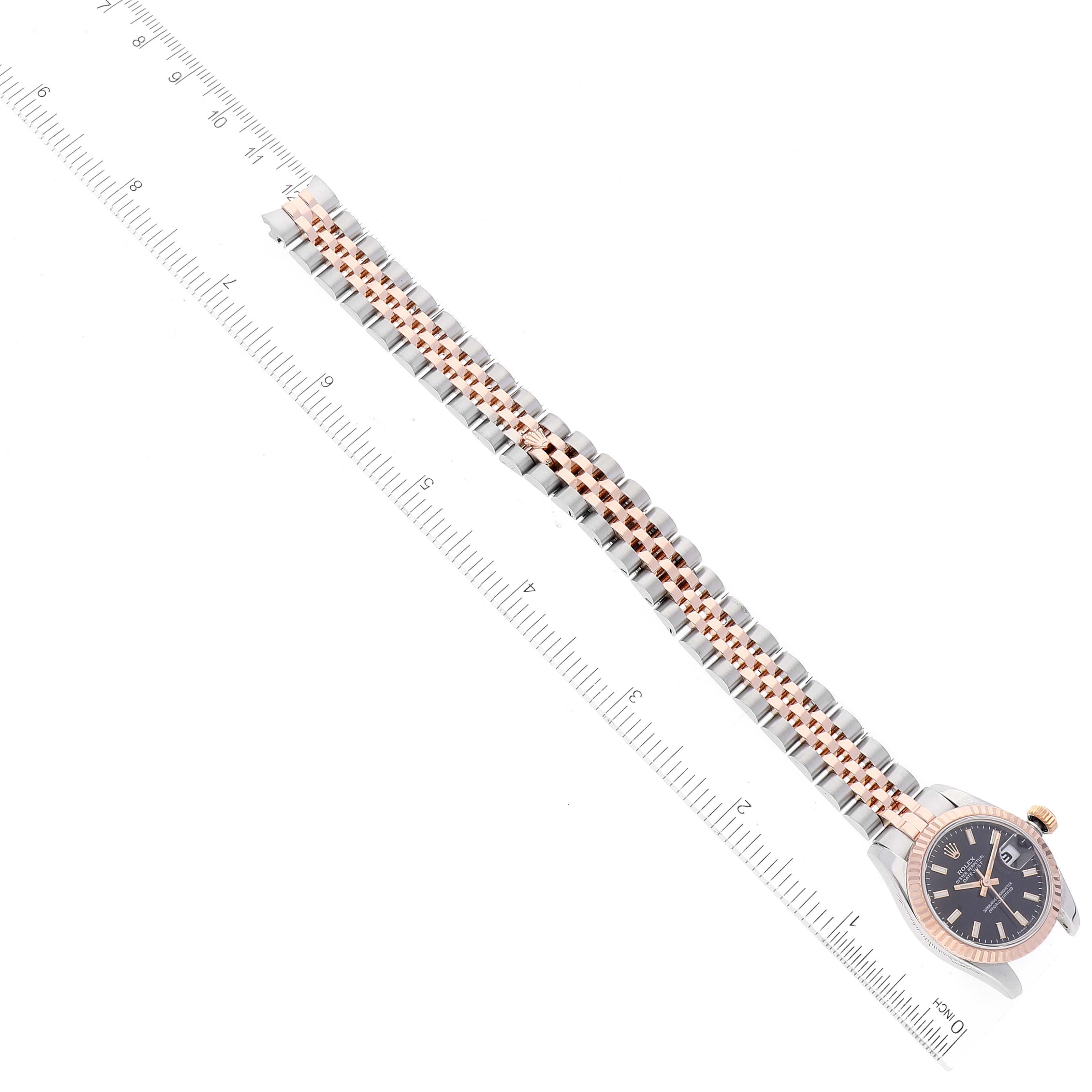 The image shows a Rolex Datejust 179171 Women's Steel and Gold (two tone) Black Dial 179171 Women's Steel and Gold (two tone) Black Dial watch with a ruler, displaying the entire band and the watch face from an overhead angle.