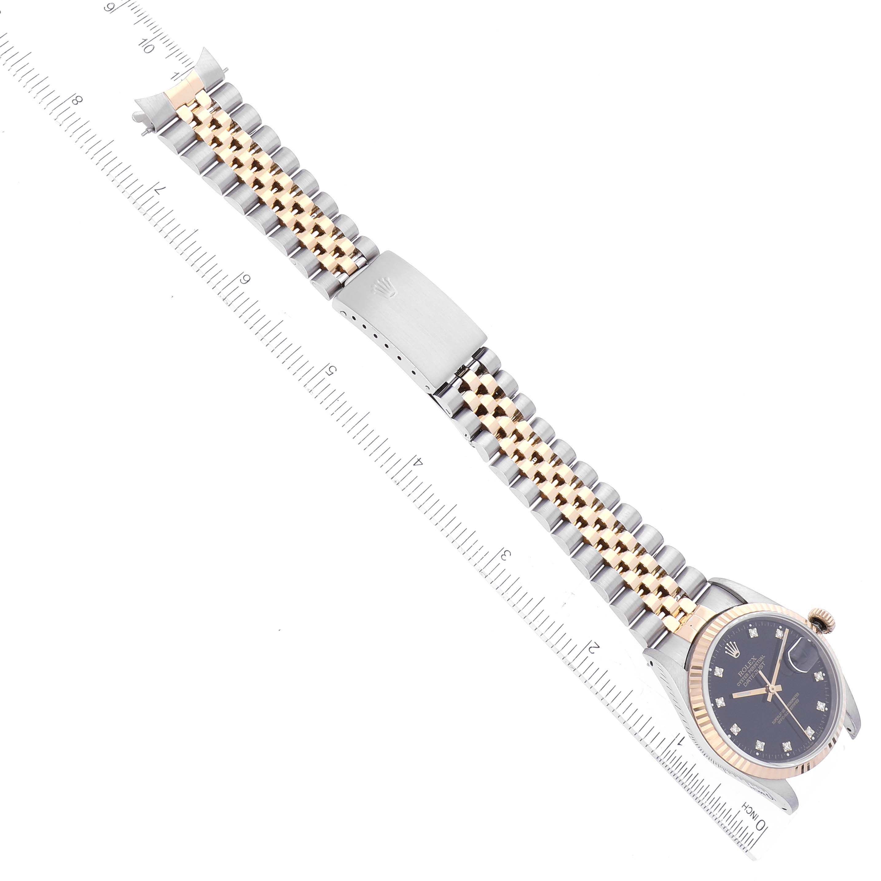 The image shows a Rolex Datejust 16233 Men's Steel and Gold (two tone) Black Dial 16233 Men's Steel and Gold (two tone) Black Dial watch at a top-down angle, featuring the full bracelet and clasp alongside a measuring ruler.