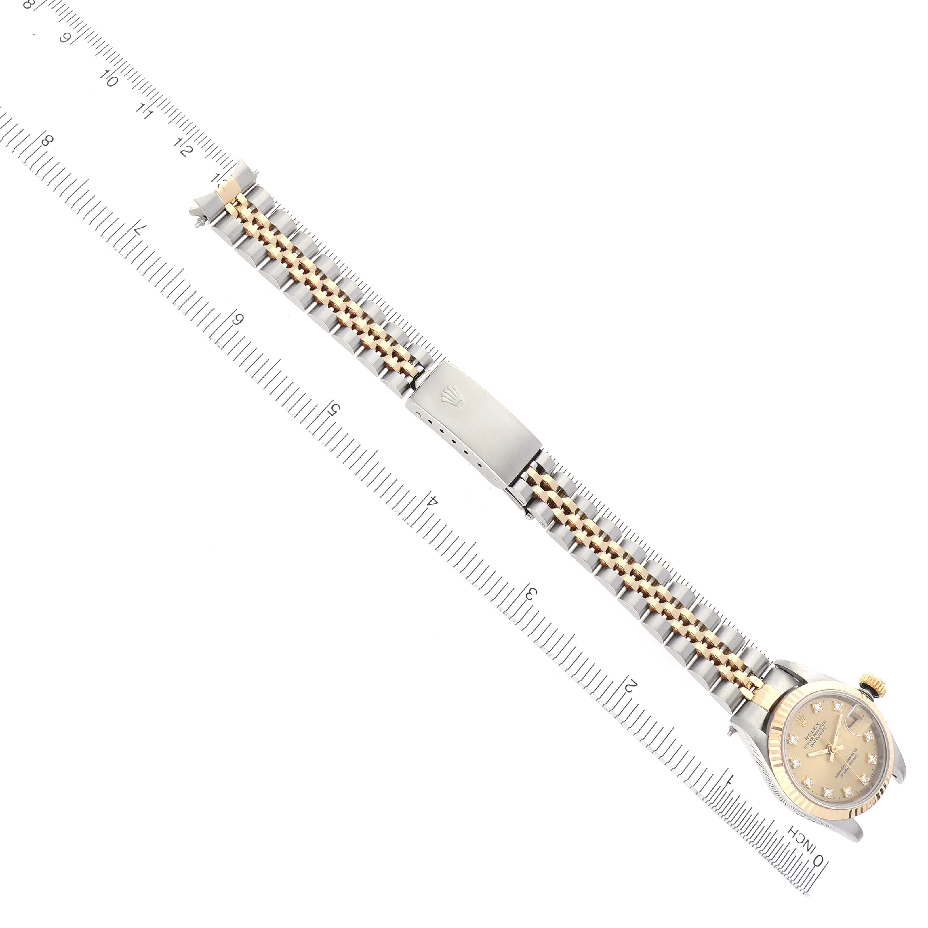 The image shows the Rolex Datejust 69173 Women
s Steel and Gold (two tone) Champagne Dial 69173 Women
s Steel and Gold (two tone) Champagne Dial watch from an overhead angle, displaying the full bracelet and dial beside a ruler.