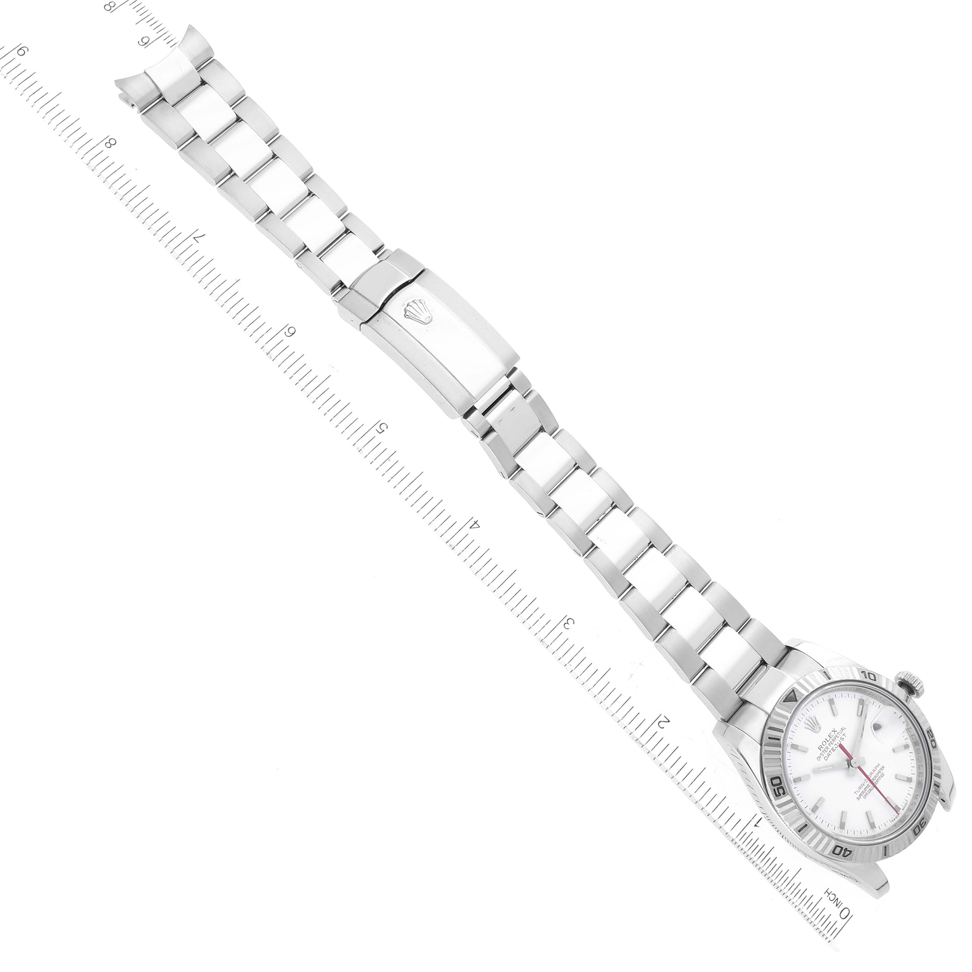 The image shows a Rolex Turn-o-Graph 116264 Men
s Stainless Steel White Dial 116264 Men
s Stainless Steel White Dial watch laid flat, displaying the face, bezel, and metal bracelet along with a ruler for scale.