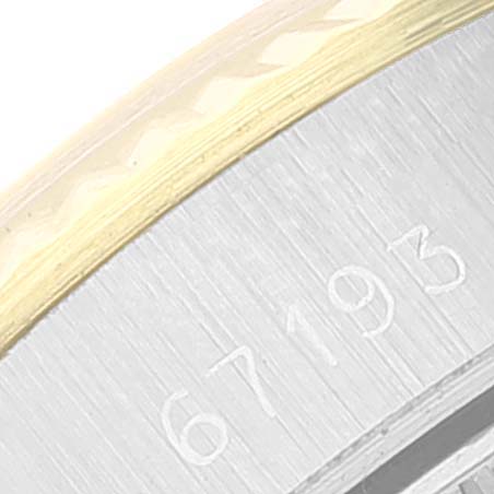 The image shows a close-up angle of the Rolex Oyster Perpetual 67193 Women
s Steel and Gold (two tone) White Dial 67193 Women
s Steel and Gold (two tone) White Dial model, focusing on the bezel and part of the serial number engraved on the case.