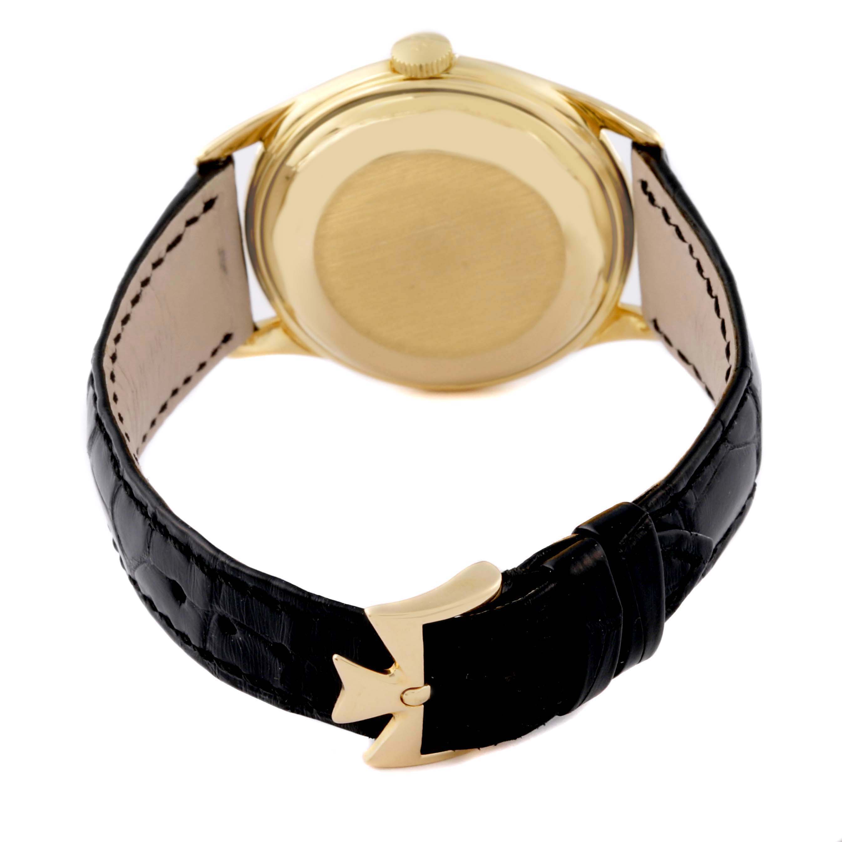 The image shows the back of the Vacheron Constantin Vintage Men's Yellow Gold Silver Dial Men's Yellow Gold Silver Dial watch, highlighting its gold case, crown, and leather strap with a gold clasp.