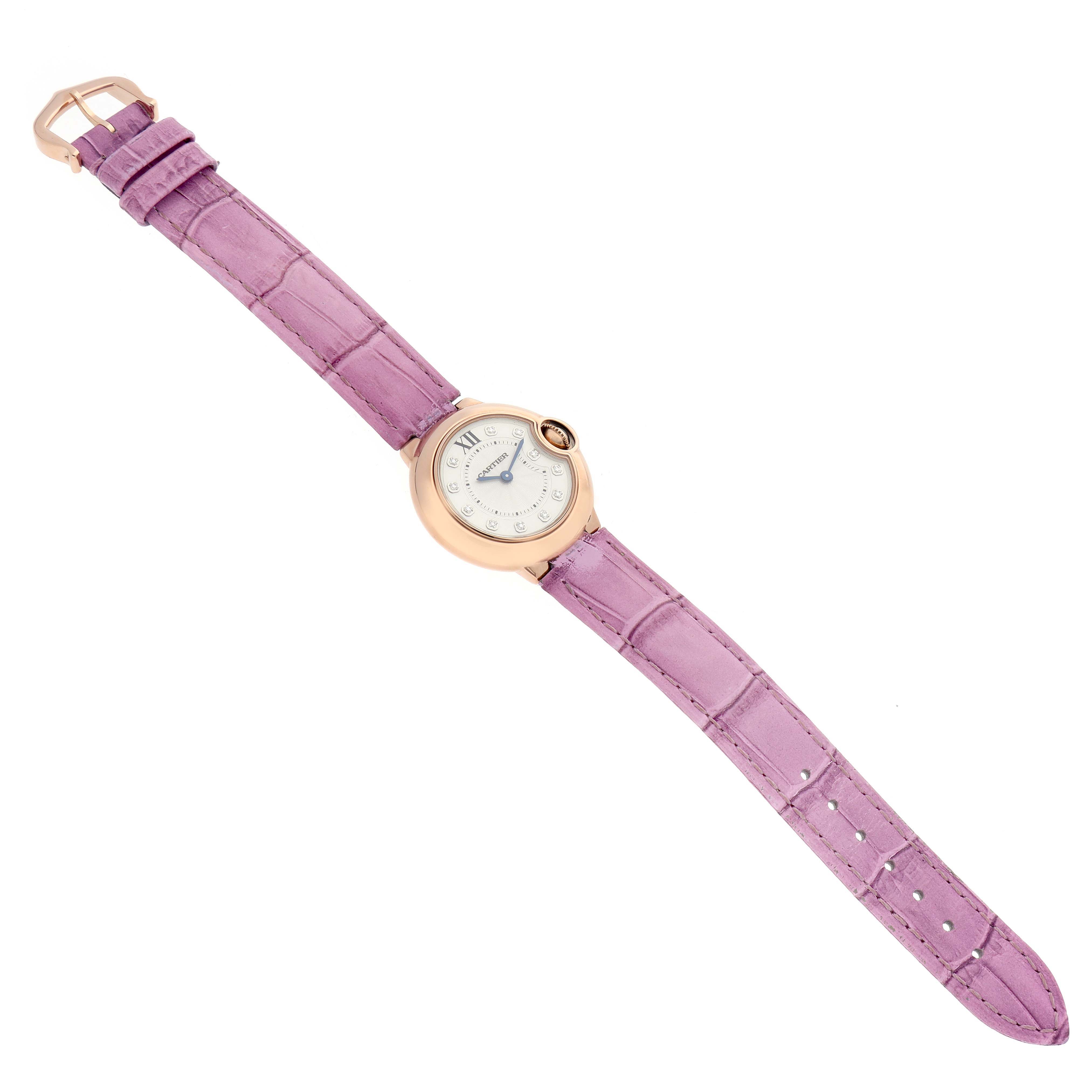 The Cartier Ballon Bleu WE902050 Women's Rose Gold Silver Dial watch is shown from a top-down angle, displaying its round case, dial, and purple leather strap.