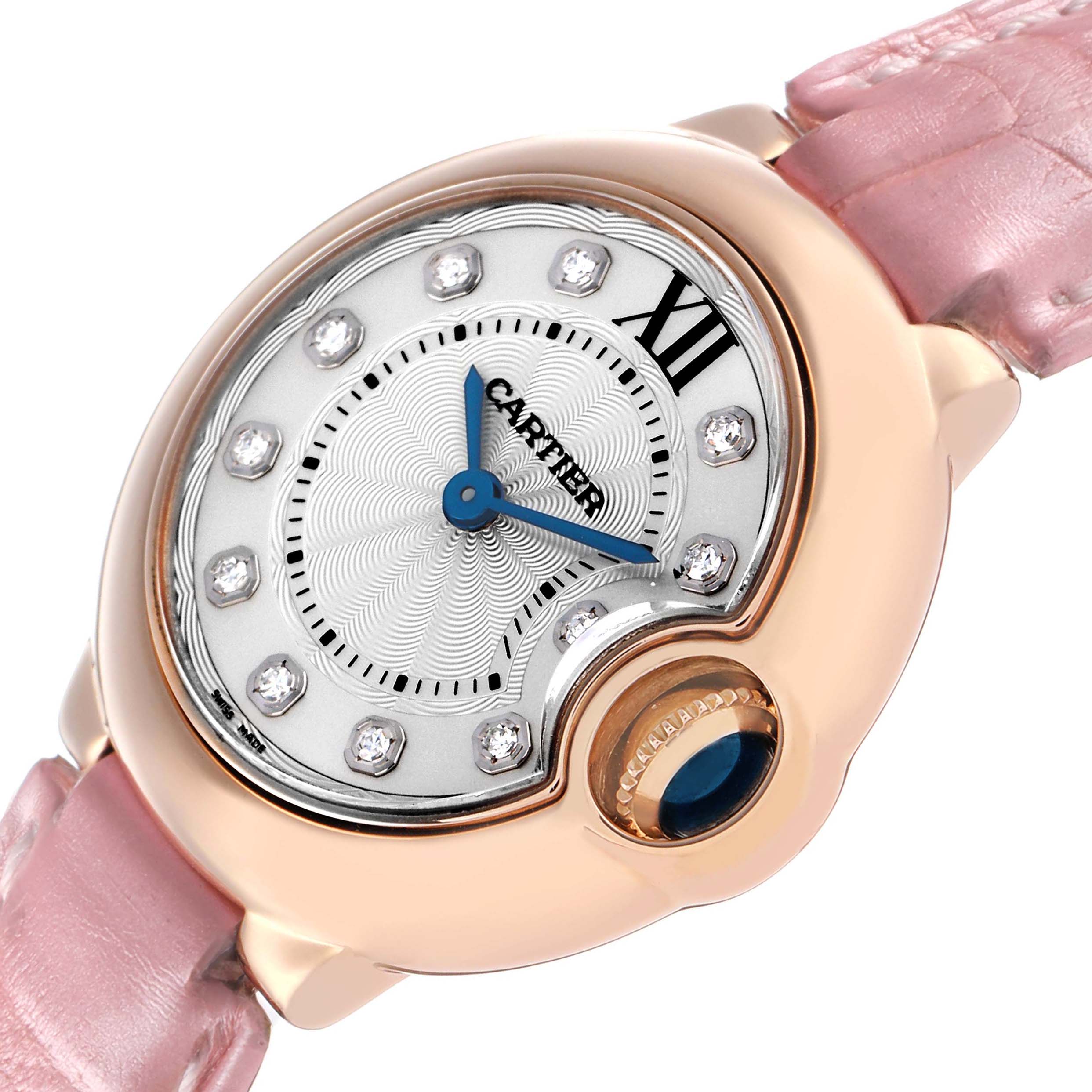 The Cartier Ballon Bleu WE902050 Women's Rose Gold Silver Dial watch is shown at an angled view, displaying the dial, pink strap, and crown with a blue cabochon.