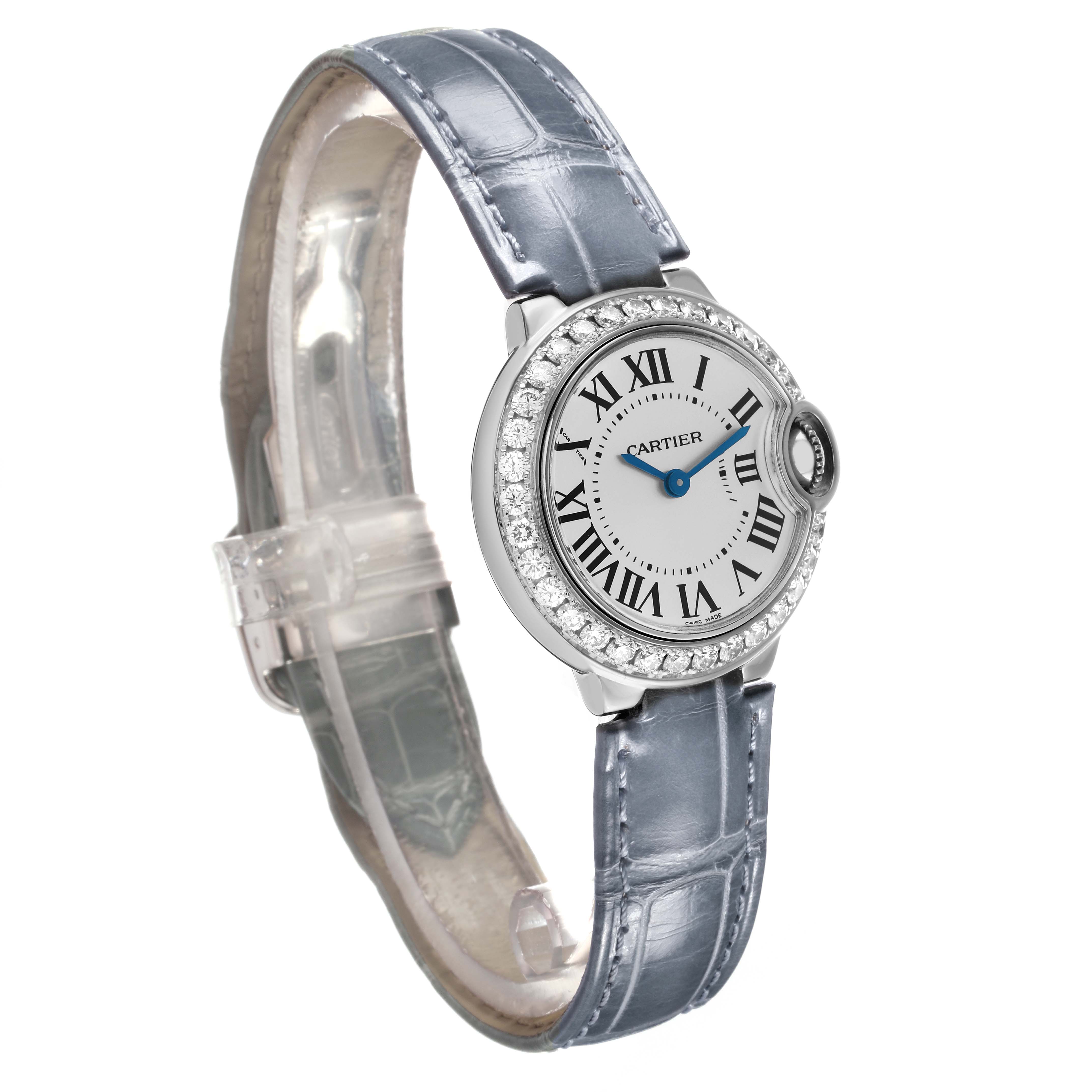 The Ballon Bleu by Cartier is shown at a three-quarter angle, highlighting its round face, Roman numerals, blue hands, and leather strap.
