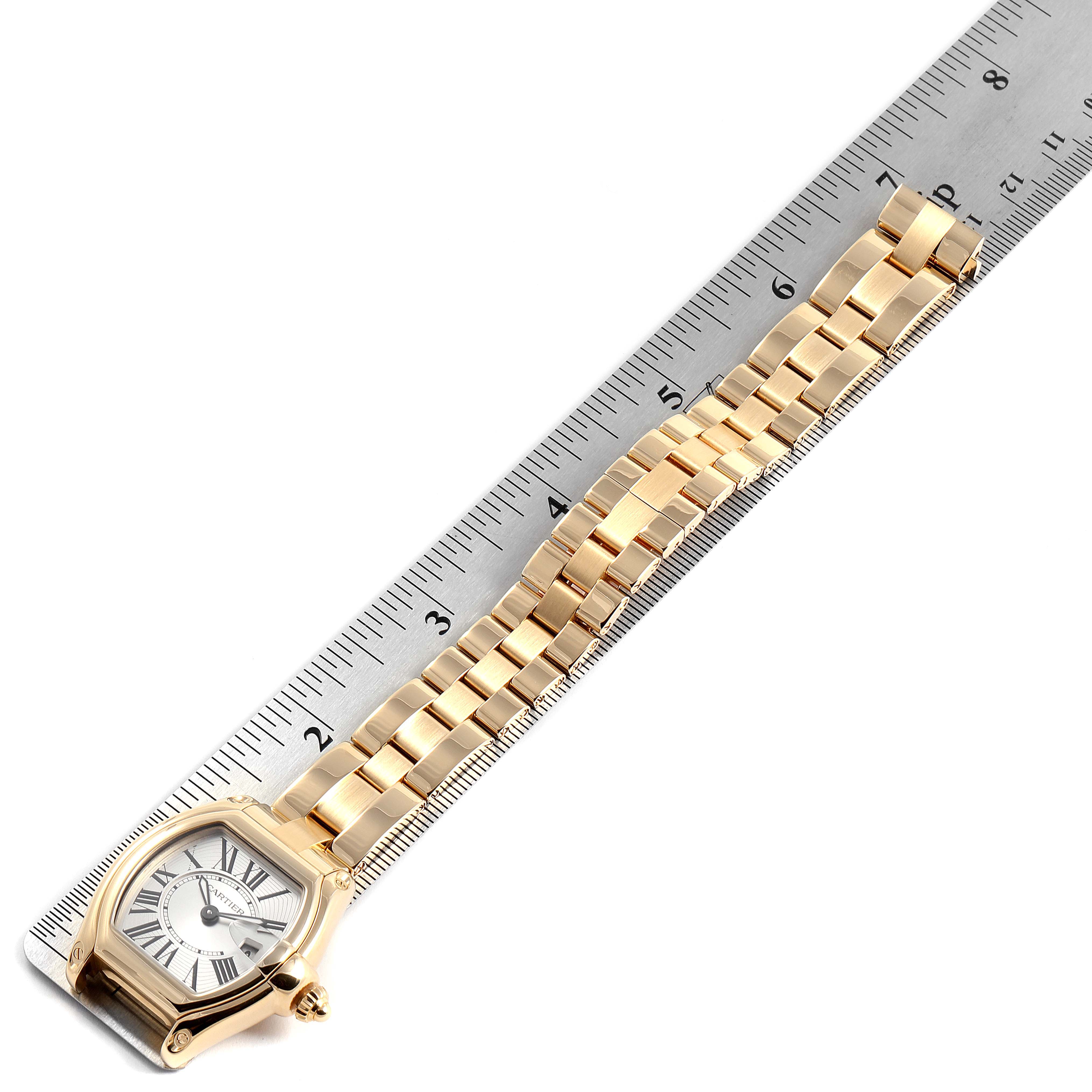 The Cartier Roadster W62018V1 Women's Yellow Gold Silver Dial W62018V1 Women's Yellow Gold Silver Dial watch is shown from a top-down angle, highlighting its face, bracelet, and a ruler for measurement.