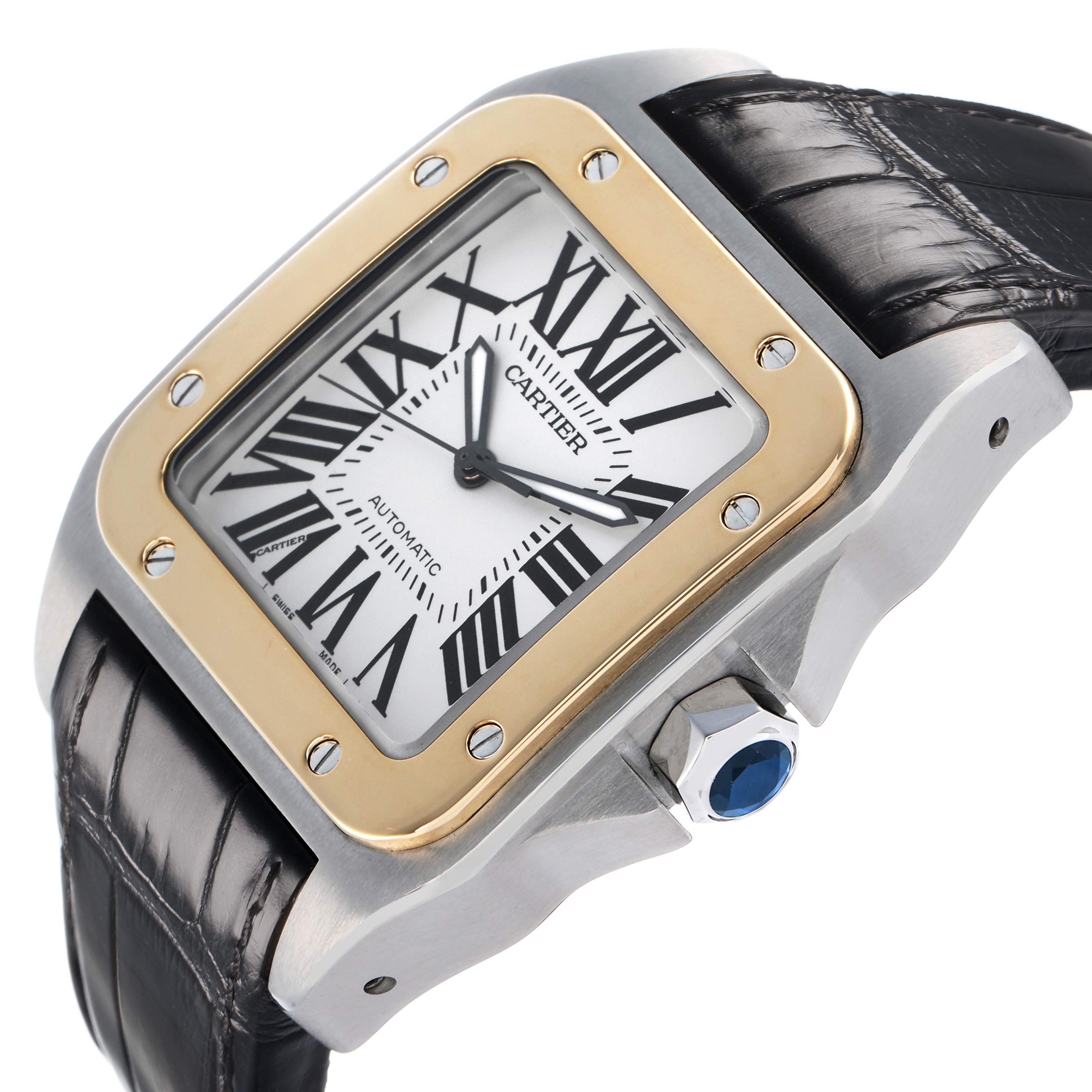 The Cartier Santos W20072X7 Men's Steel and Gold (two tone) Silver Dial watch is shown at an angle highlighting the case, bezel, crown with a blue gem, and leather strap.