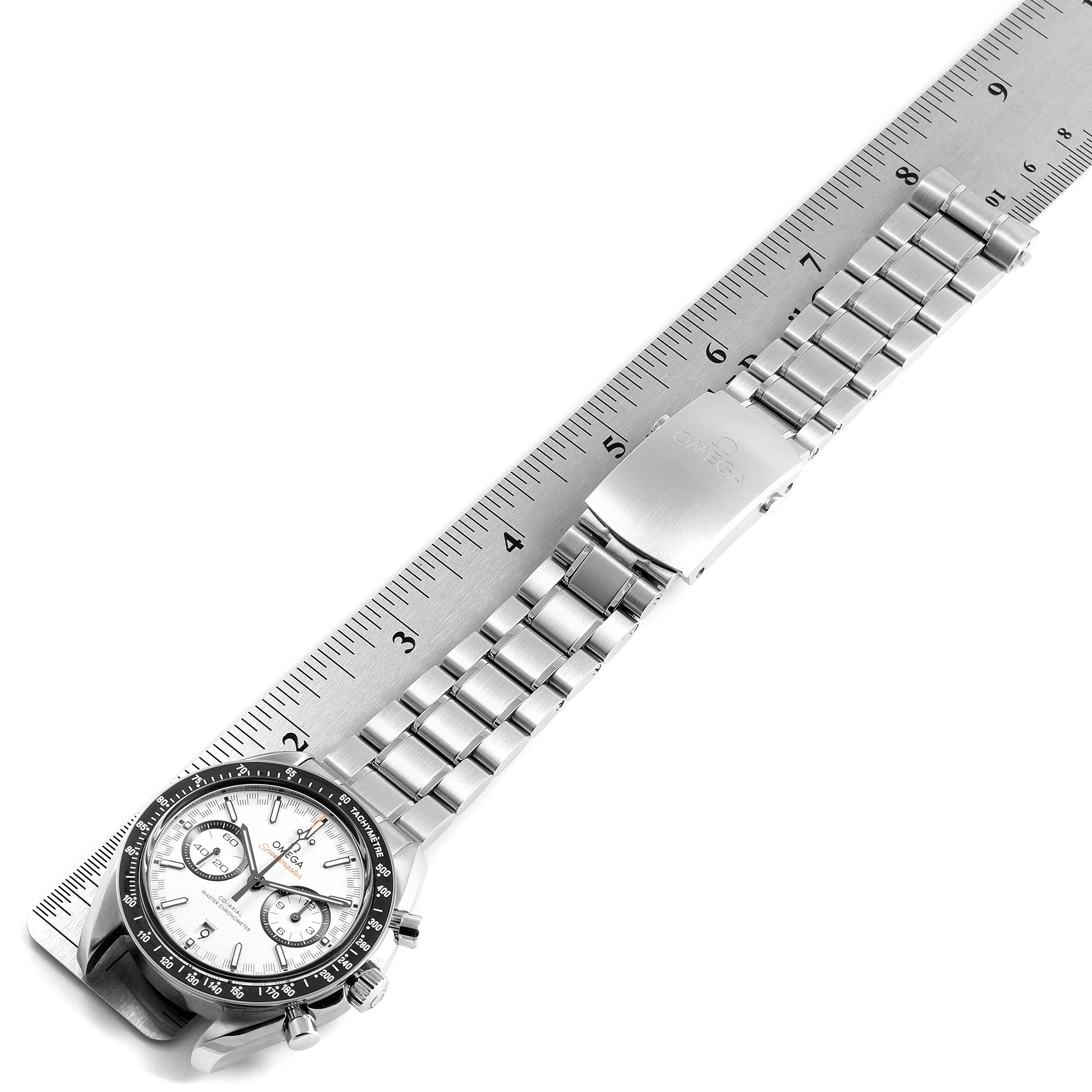 The image shows an Omega Speedmaster 40257 Men
s Stainless Steel White Dial 40257 Men
s Stainless Steel White Dial watch laid next to a ruler, displaying its face, bezel, and metal bracelet at an angle.
