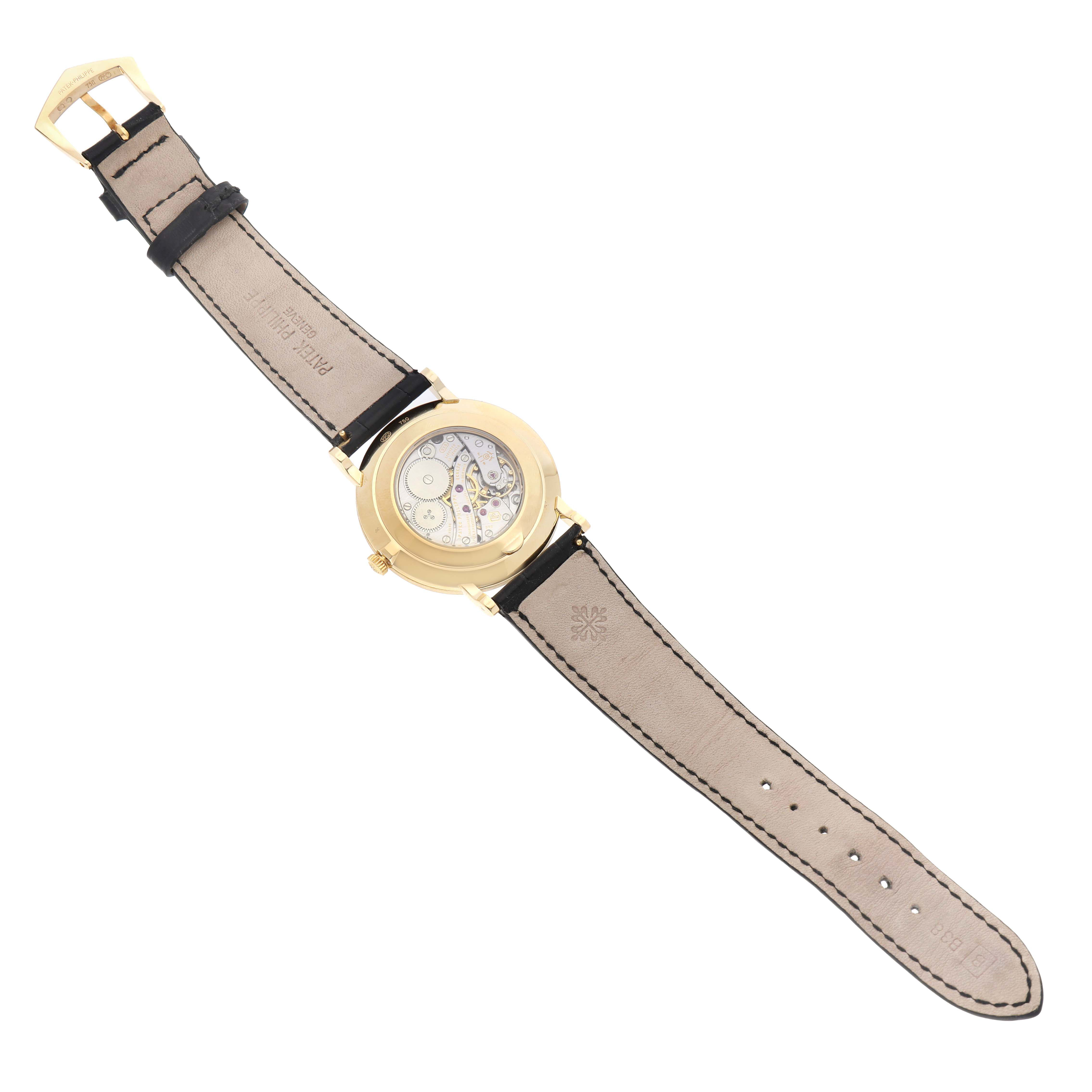 The Patek Philippe Calatrava 5119J-001 Men's Yellow Gold White Dial watch is shown from the back, highlighting the transparent case back and mechanical movement.