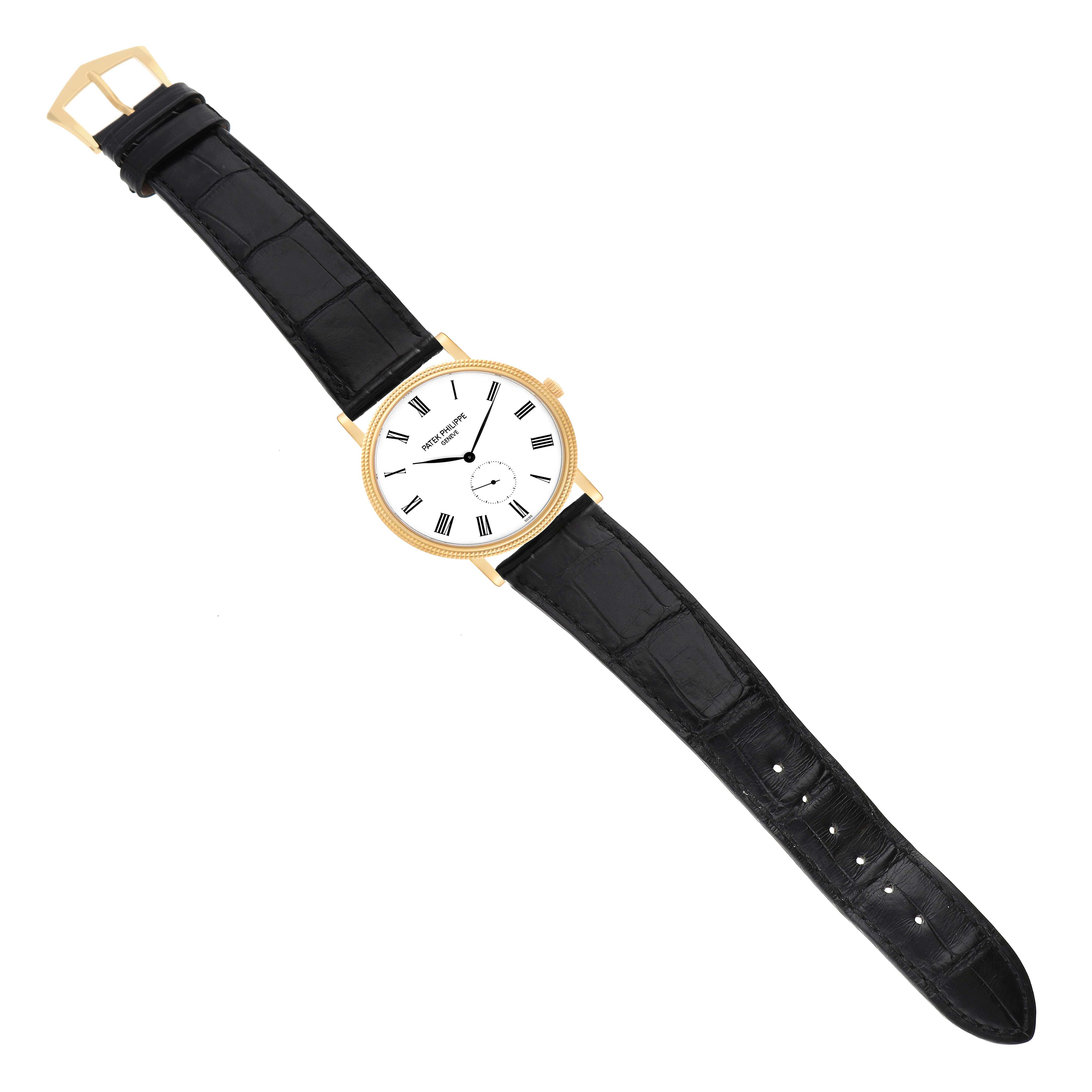 The Patek Philippe Calatrava 5119J-001 Men's Yellow Gold White Dial watch is shown from a top-down angle, displaying the face, black leather strap, and gold buckle.