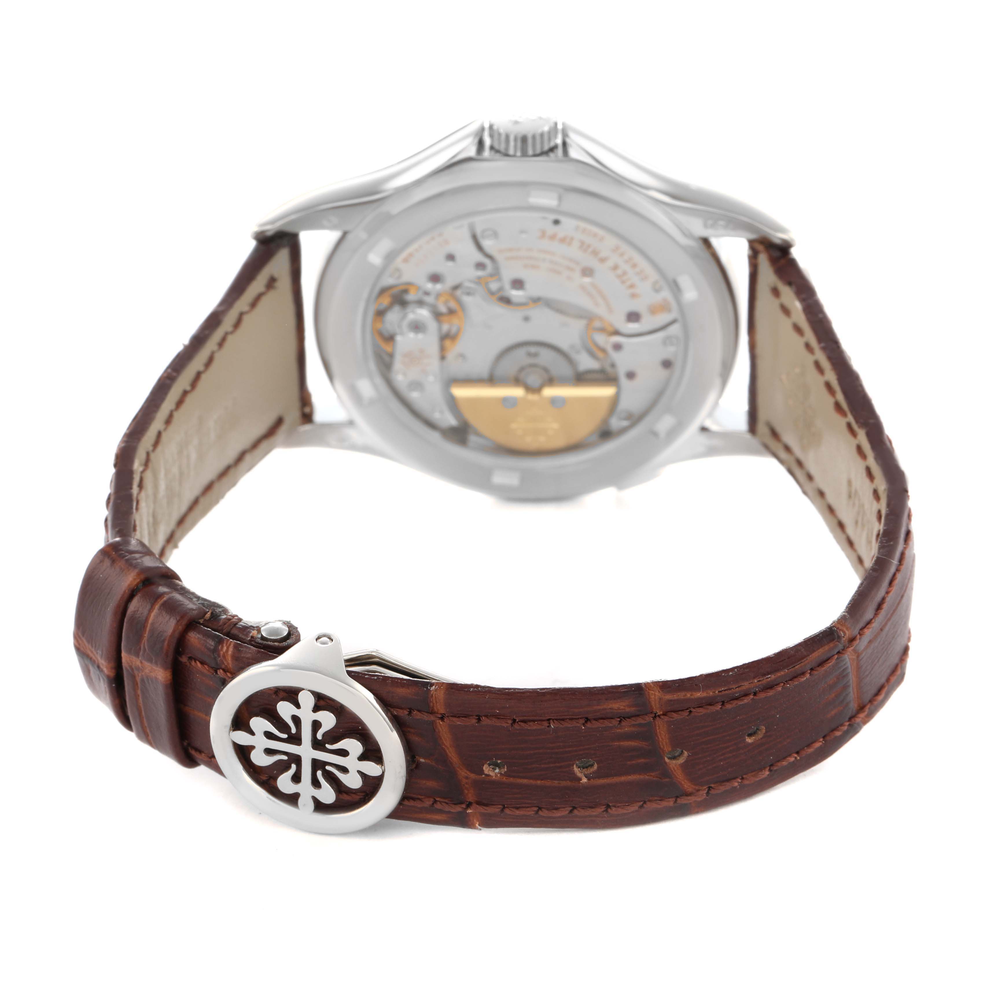 The image shows the back view of a Patek Philippe Complications 5110G Men's White Gold Silver Dial watch, highlighting its movement and leather strap with a clasp.