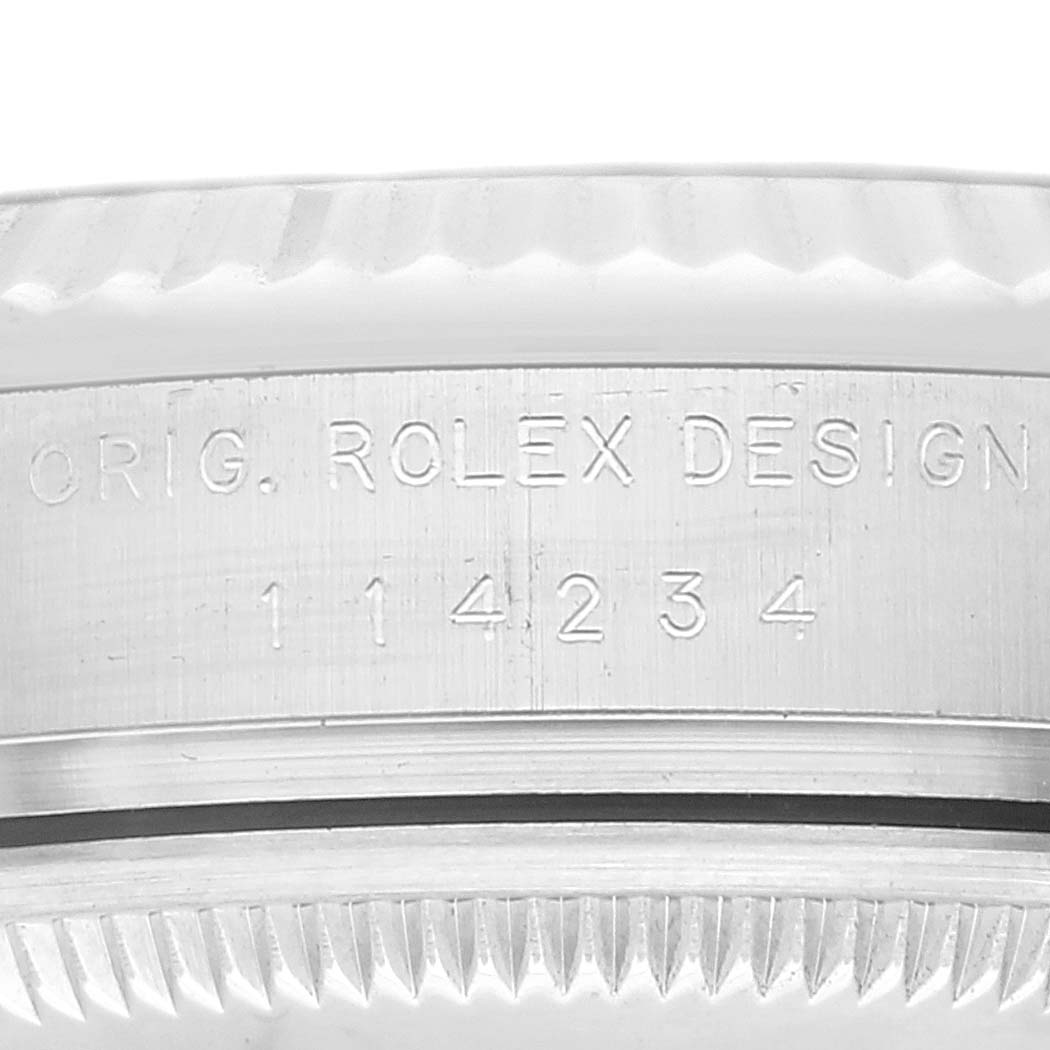 This close-up image shows the engraved model number and part of the bezel of a Rolex Air-King 114234 Men's Stainless Steel White Dial 114234 Men's Stainless Steel White Dial watch.