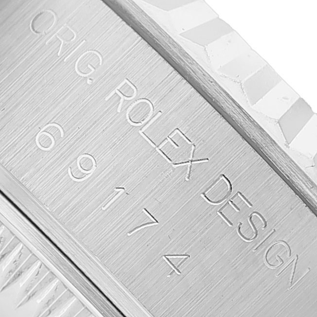 The image shows a close-up of the engraved side of a Rolex Datejust 69174 Women's Stainless Steel White Dial watch featuring the model number and "ROLEX DESIGN" text.