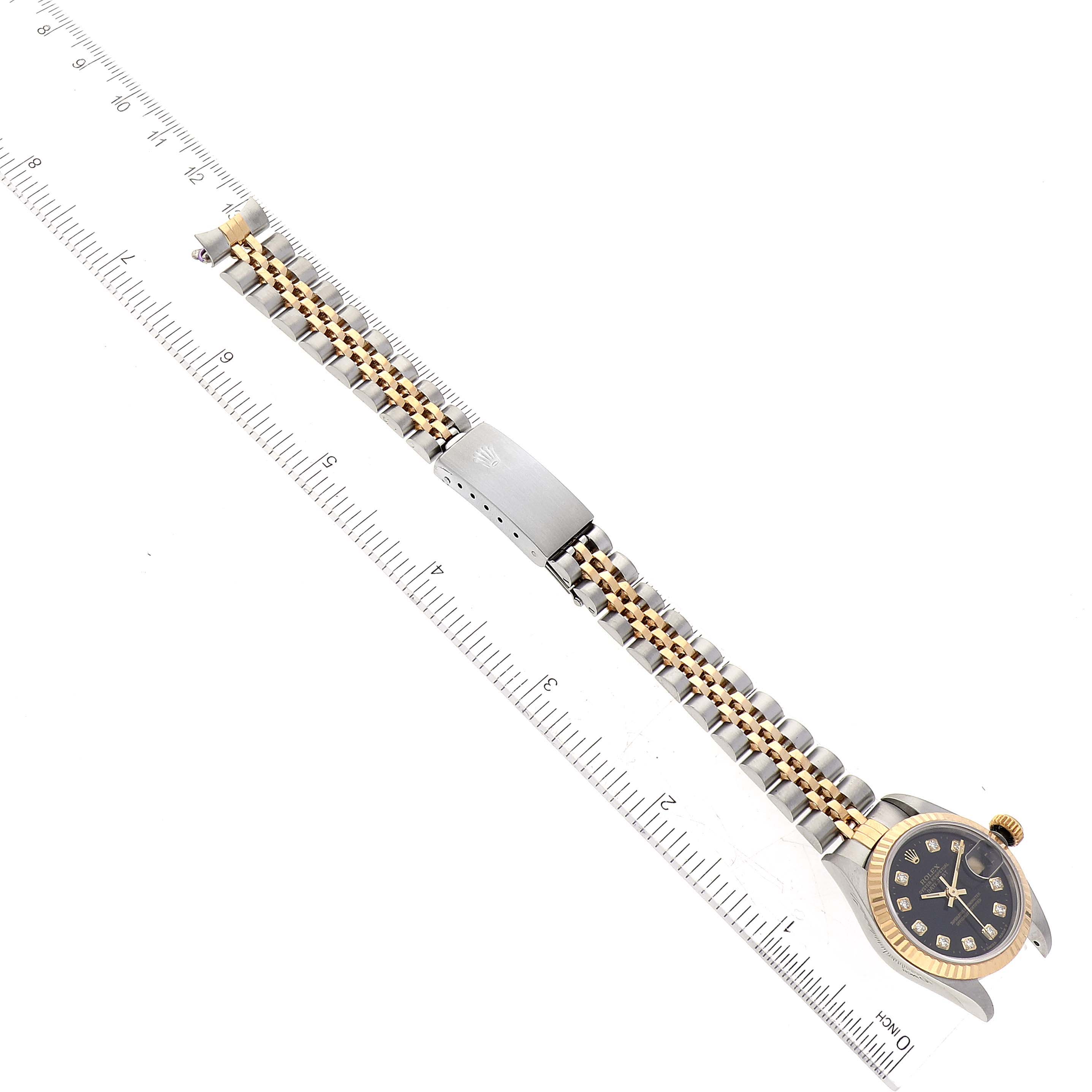 The Rolex Datejust 69173 Women's Steel and Gold (two tone) Black Dial 69173 Women's Steel and Gold (two tone) Black Dial watch is shown from a top-down angle with its bracelet fully extended and a ruler next to it.