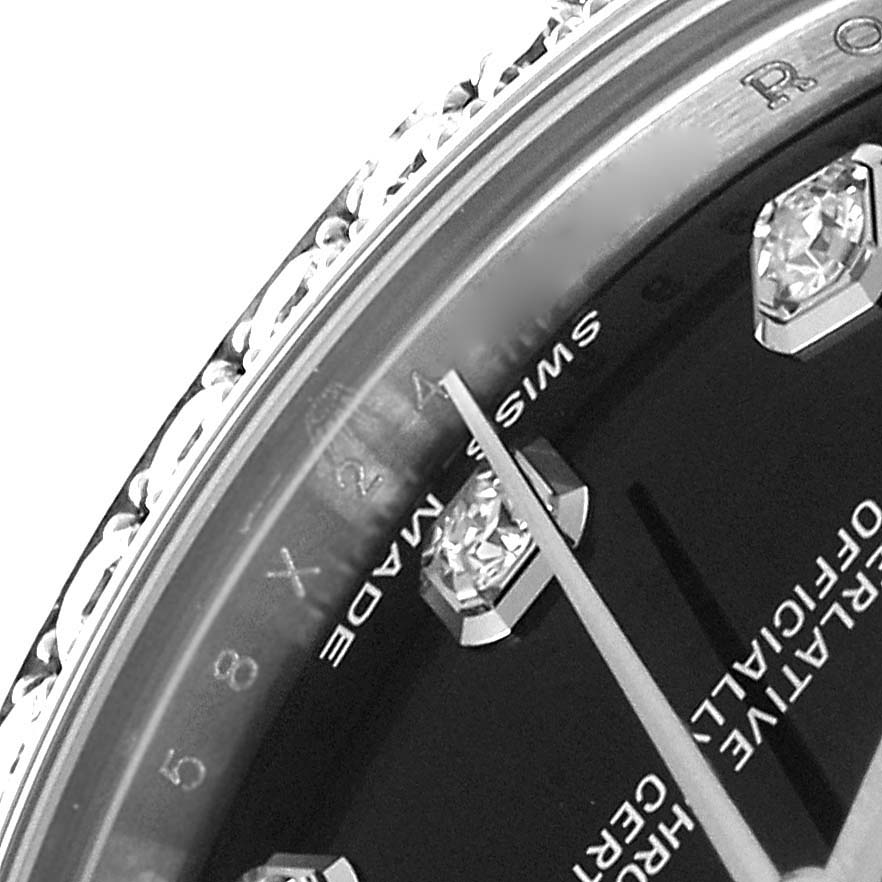 This angled close-up of a Rolex Mid-Size 178384 Women
s Stainless Steel Black Dial 178384 Women
s Stainless Steel Black Dial watch shows the dial, diamond markers, and bezel, with partial text on the dial.