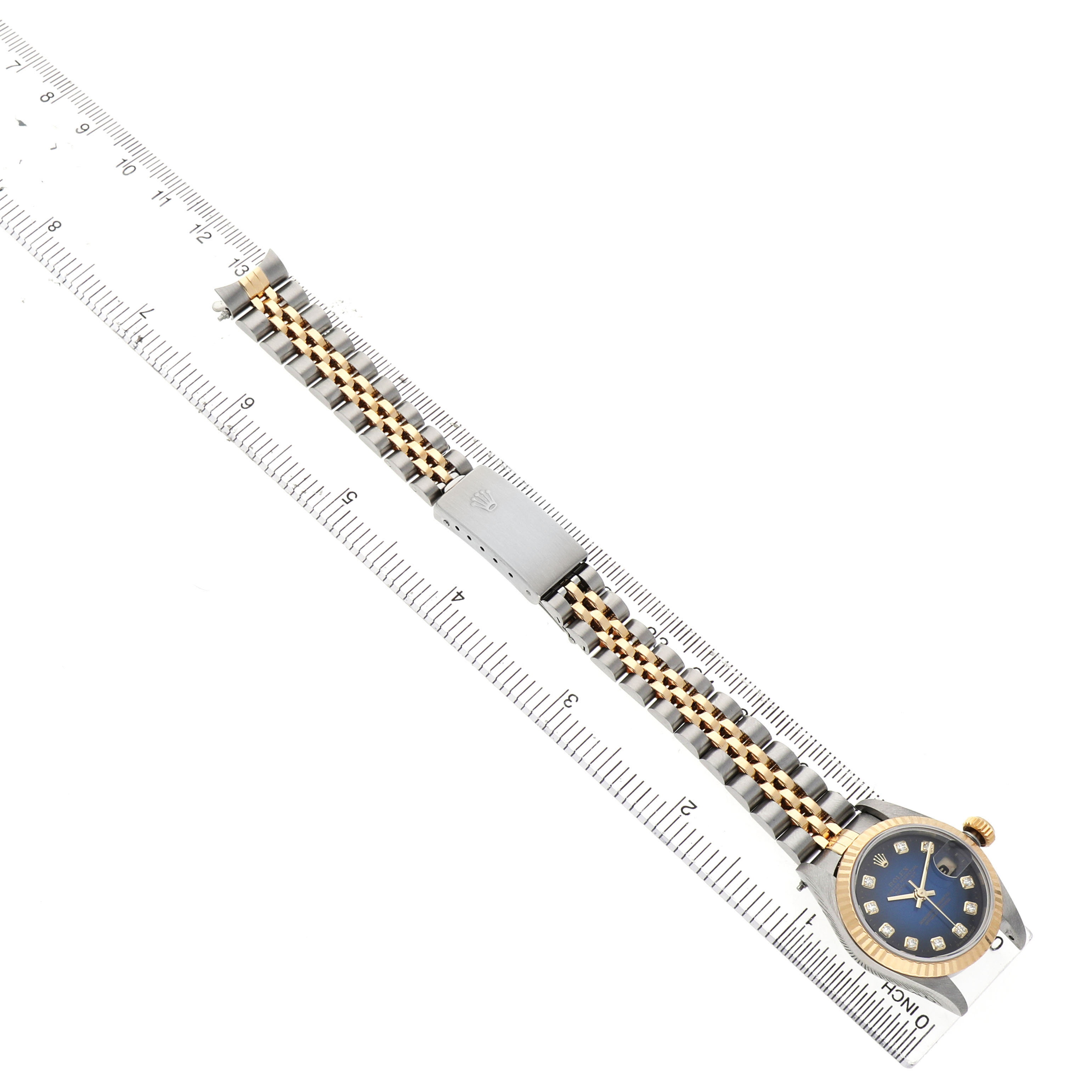 The Rolex Datejust 79173 Women's Stainless Steel Blue Dial watch is shown from an overhead angle, highlighting the bracelet and clasp next to a ruler.