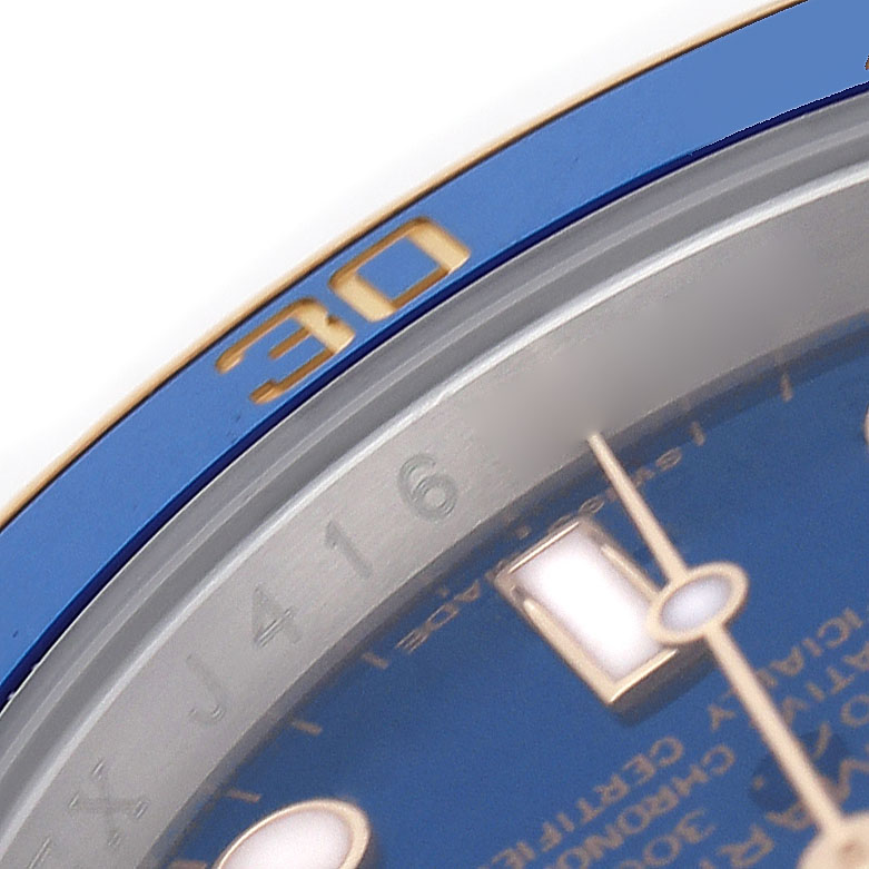The image shows a close-up of the Rolex Submariner 116613 Men's Steel and Gold (two tone) Blue Dial's blue bezel, part of the dial, and hands at an angled view.