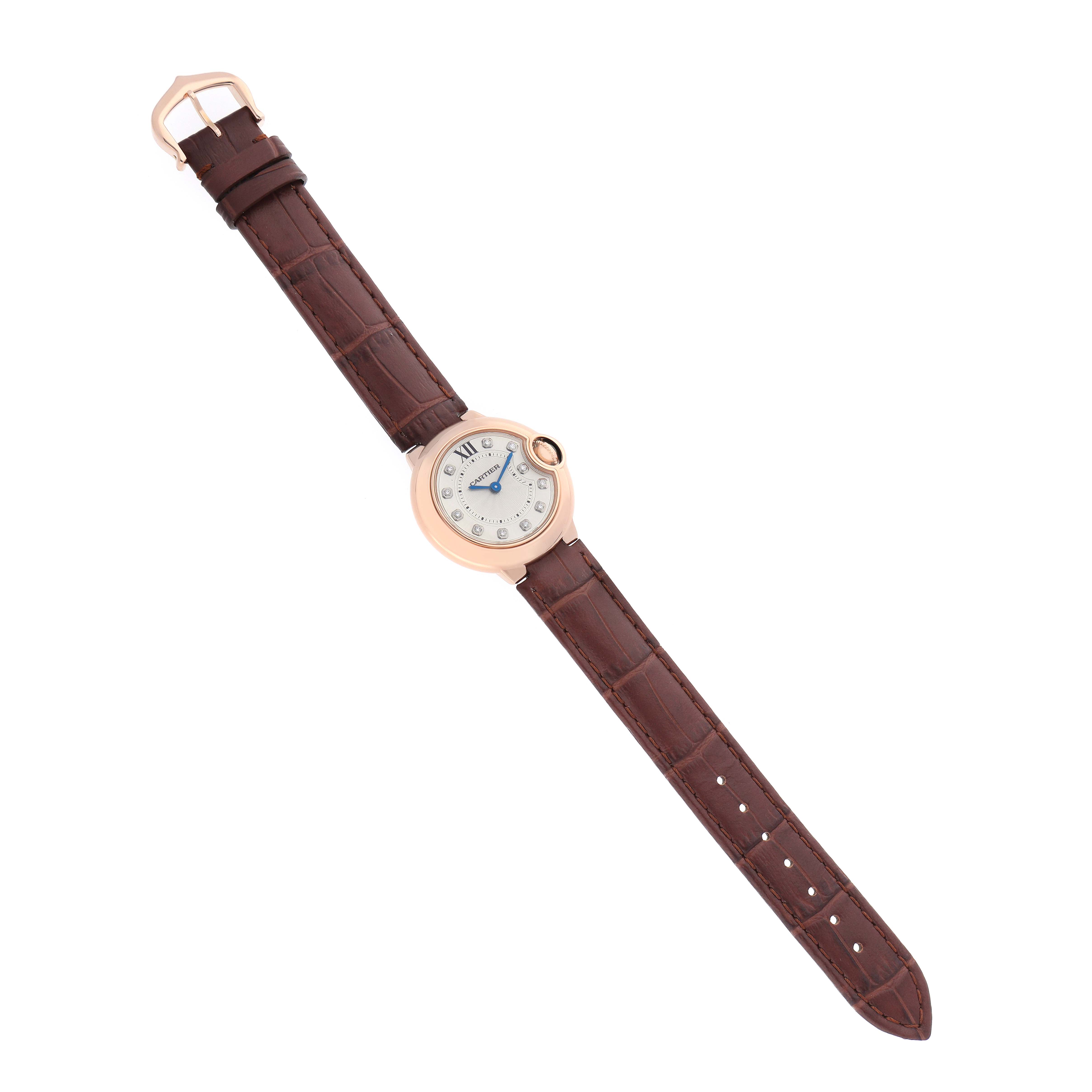 The Cartier Ballon Bleu WJBB0019 Women's Rose Gold Silver Dial watch is shown from a top-down angle, displaying its round face, blue hands, and brown leather strap.