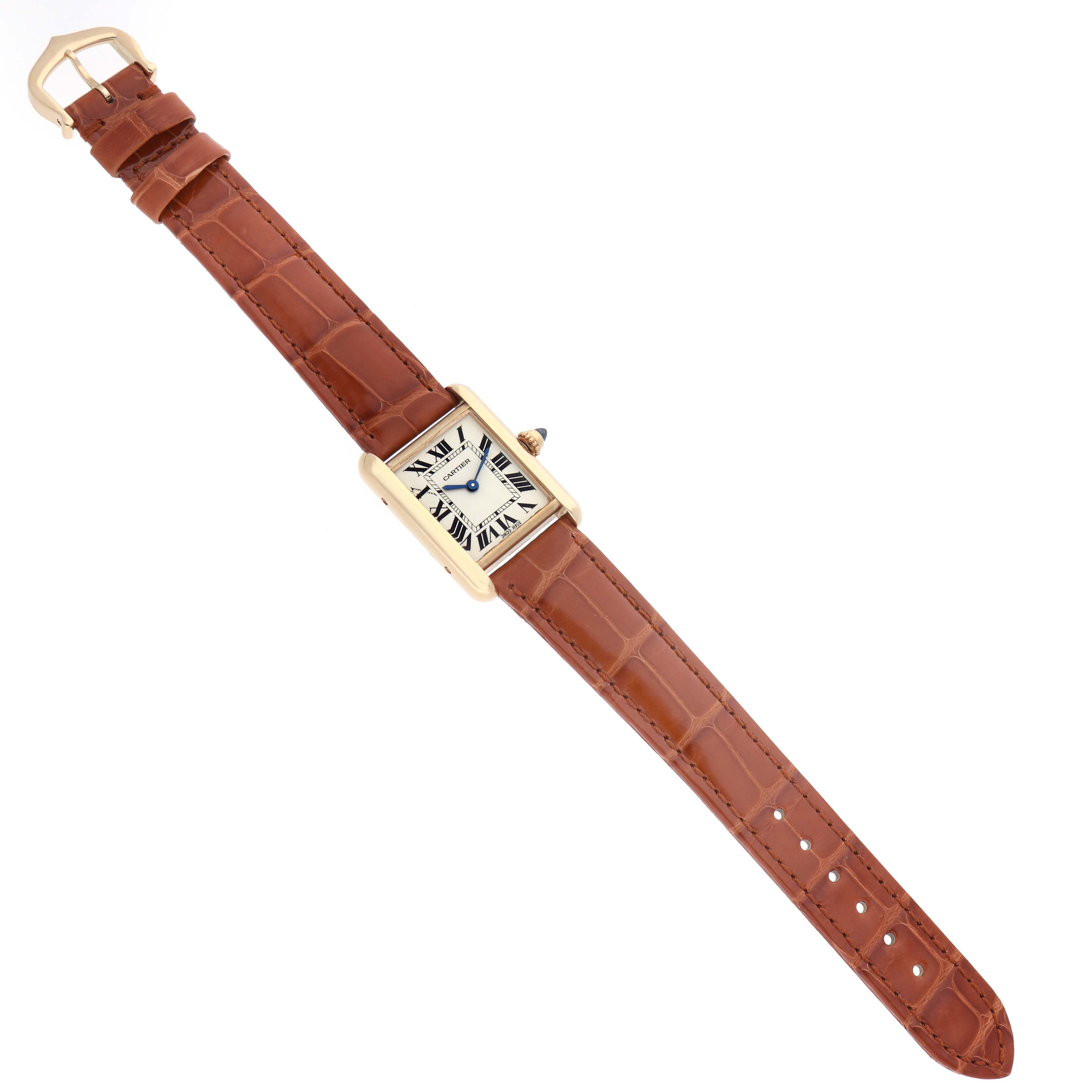The Cartier Tank Louis W1529856 Women's Yellow Gold Silver Dial watch is shown from a top-down angle, displaying the face, bezel, and brown leather strap with a buckle.