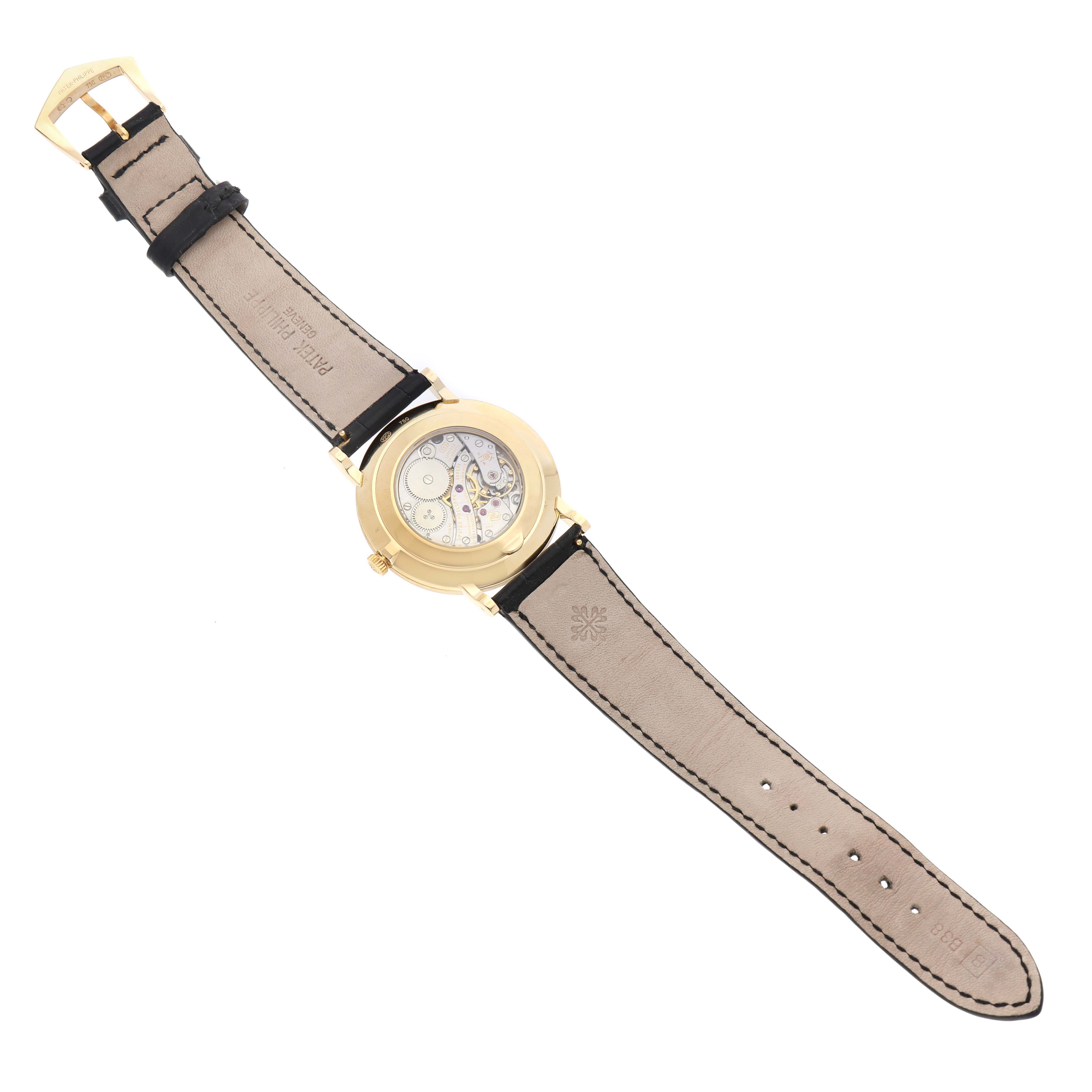 The image shows the back of a Patek Philippe Calatrava 5119J-001 Men's Yellow Gold White Dial watch, highlighting the movement and leather strap.