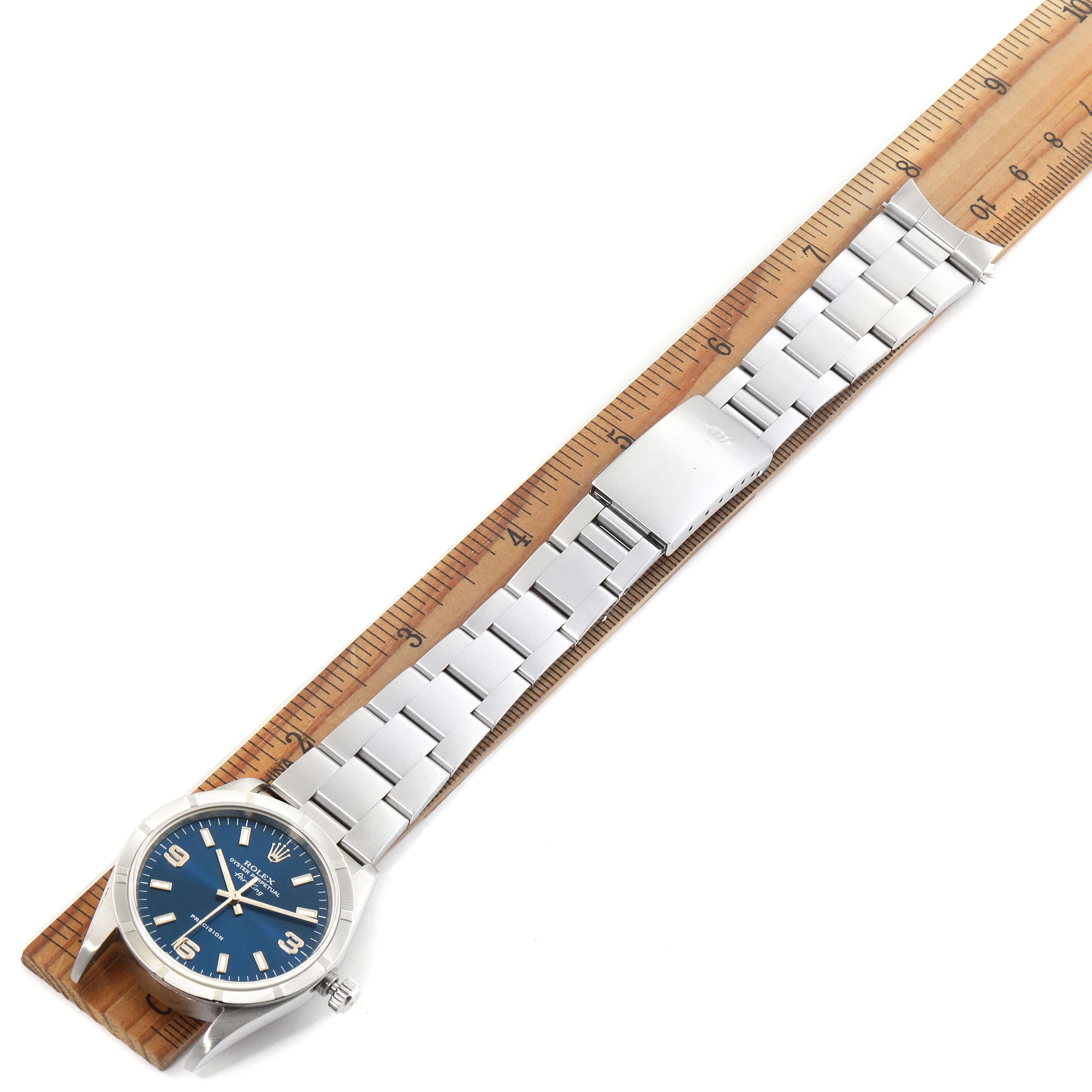 The Rolex Air-King 14010 Men's Stainless Steel Blue Dial 14010 Men's Stainless Steel Blue Dial watch is shown from a top-down angle, laying flat next to a ruler, displaying the bracelet and blue dial.
