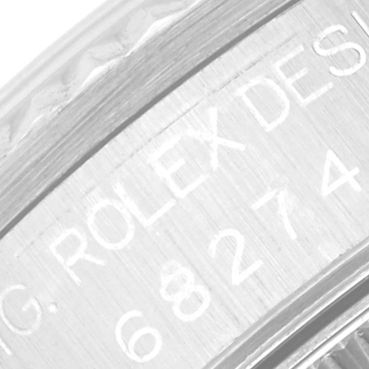 The image shows an angled close-up of the mid-size Rolex model, focusing on the engraved side details of the bezel.
