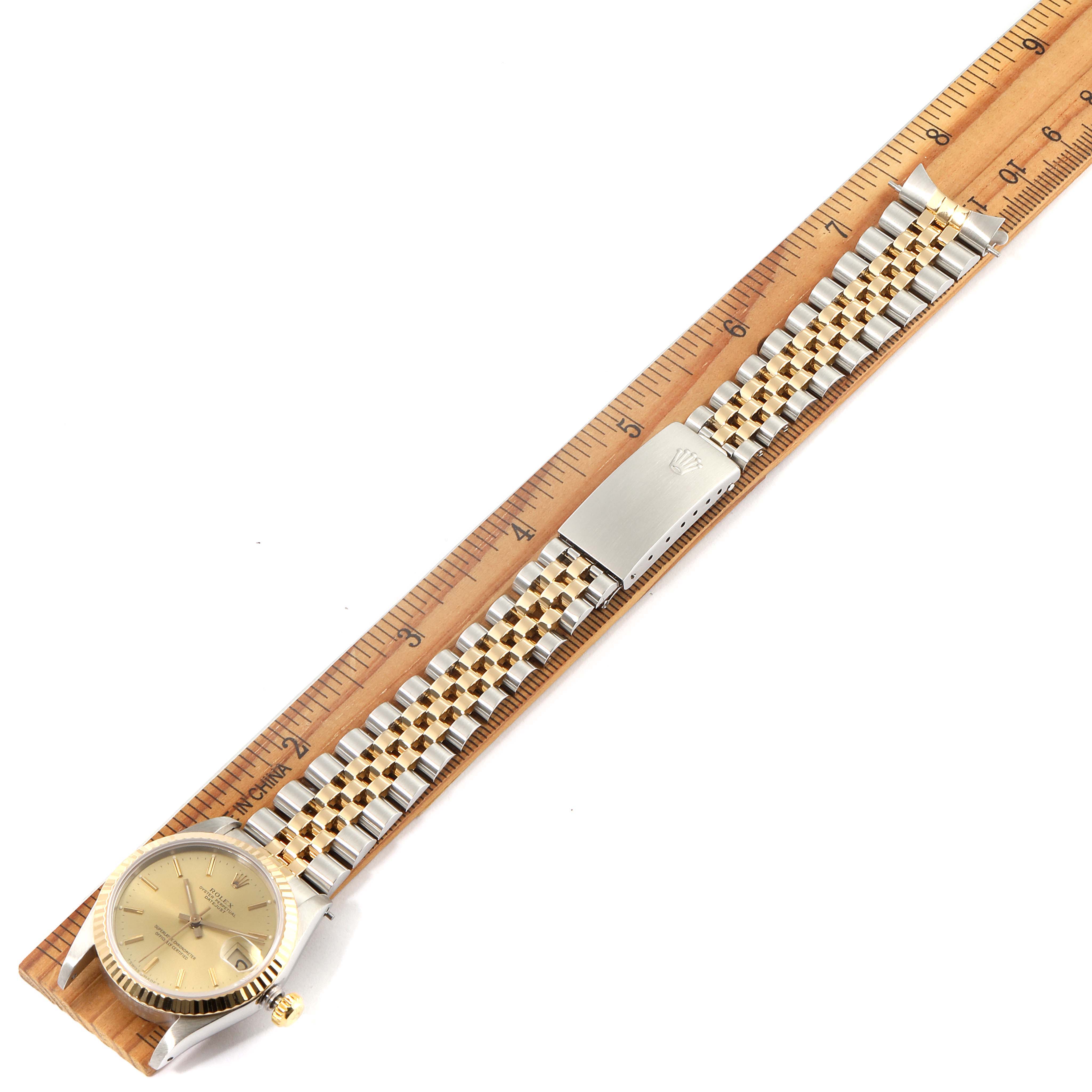 The image shows a top view of a Rolex Mid-Size 68273 Women's Steel and Gold (two tone) Champagne Dial 68273 Women's Steel and Gold (two tone) Champagne Dial watch laid flat on a ruler, displaying the face, bracelet, and clasp.