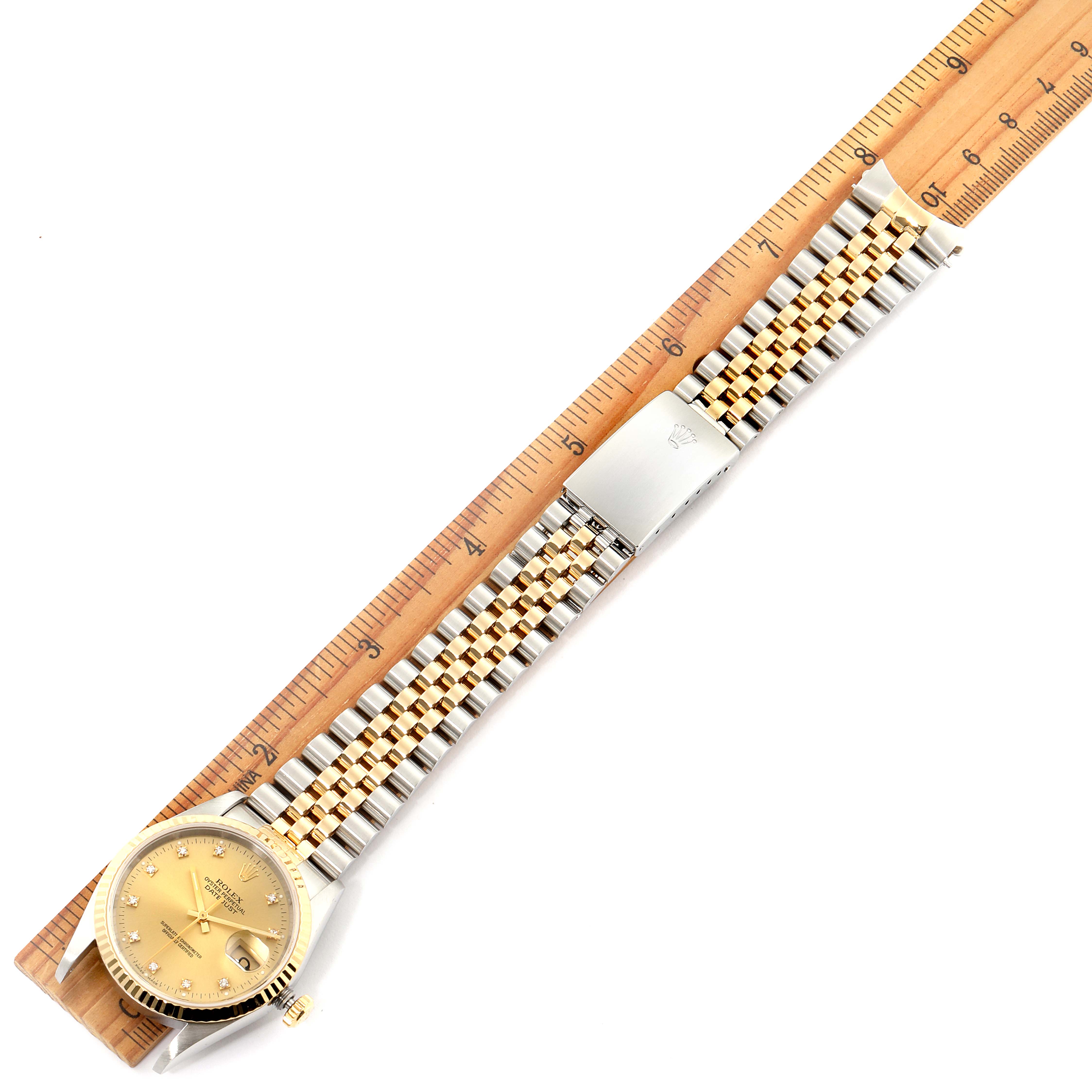 The image shows a Rolex Datejust 16233 Men's Steel and Gold (two tone) Champagne Dial 16233 Men's Steel and Gold (two tone) Champagne Dial watch laid flat with its bracelet extended and measured alongside a wooden ruler.