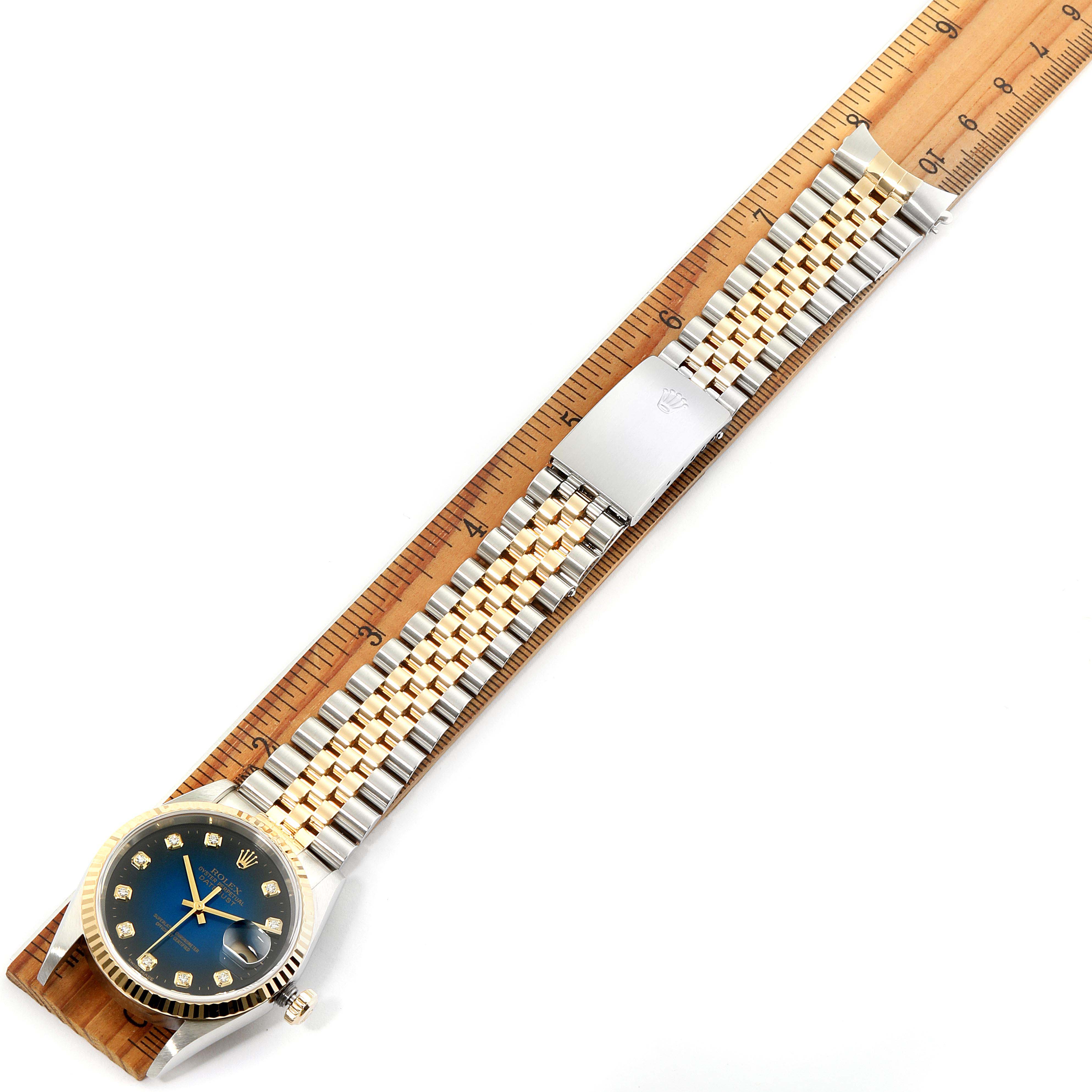 The image shows a top-down view of a Rolex Datejust 16233 Men's Steel and Gold (two tone) Blue Dial 16233 Men's Steel and Gold (two tone) Blue Dial watch, including the face, band, and clasp, with a ruler for scale.