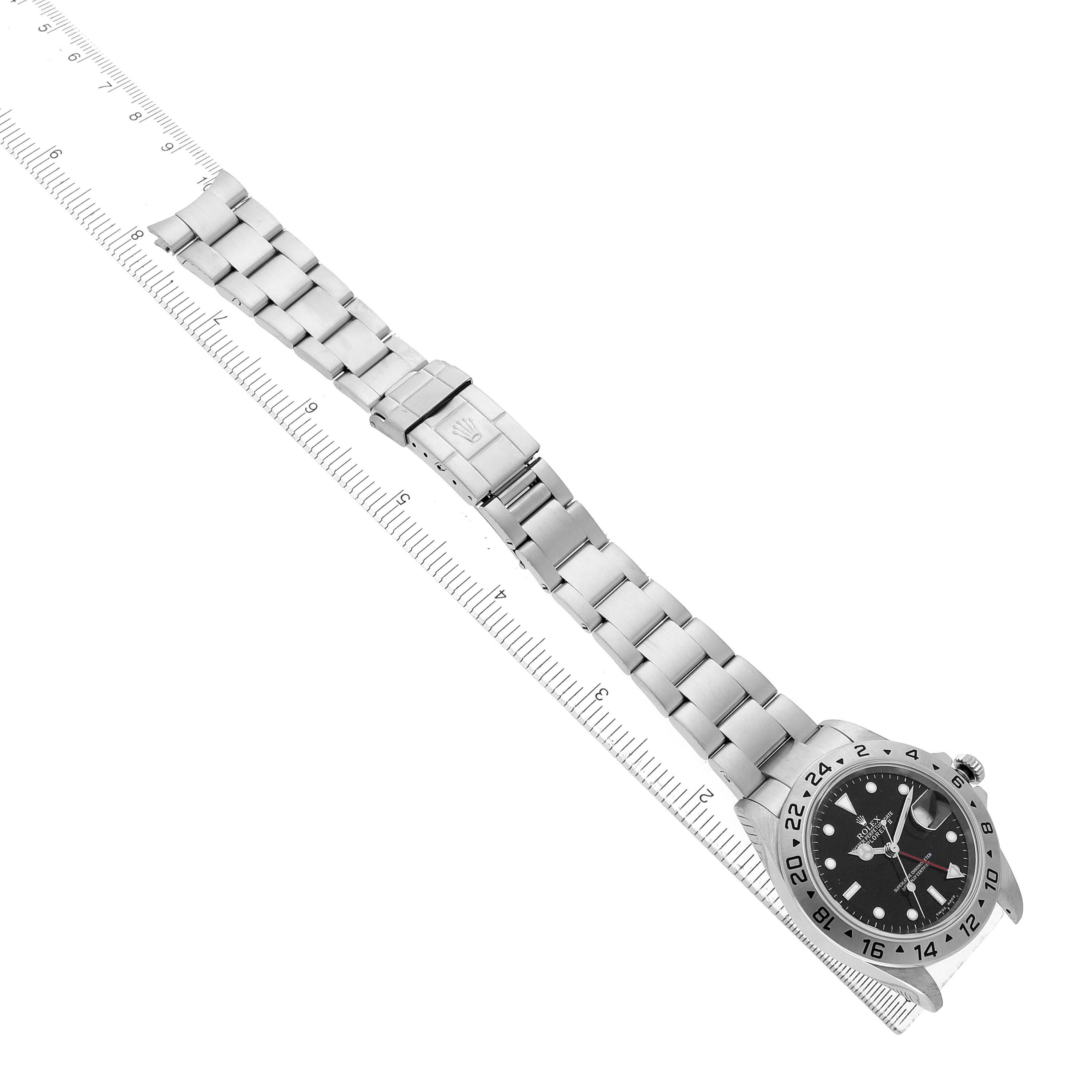 The Rolex Explorer 16570 Men's Stainless Steel Black Dial watch is shown from a top-down angle, highlighting the bracelet, clasp, and dial alongside a ruler for scale.