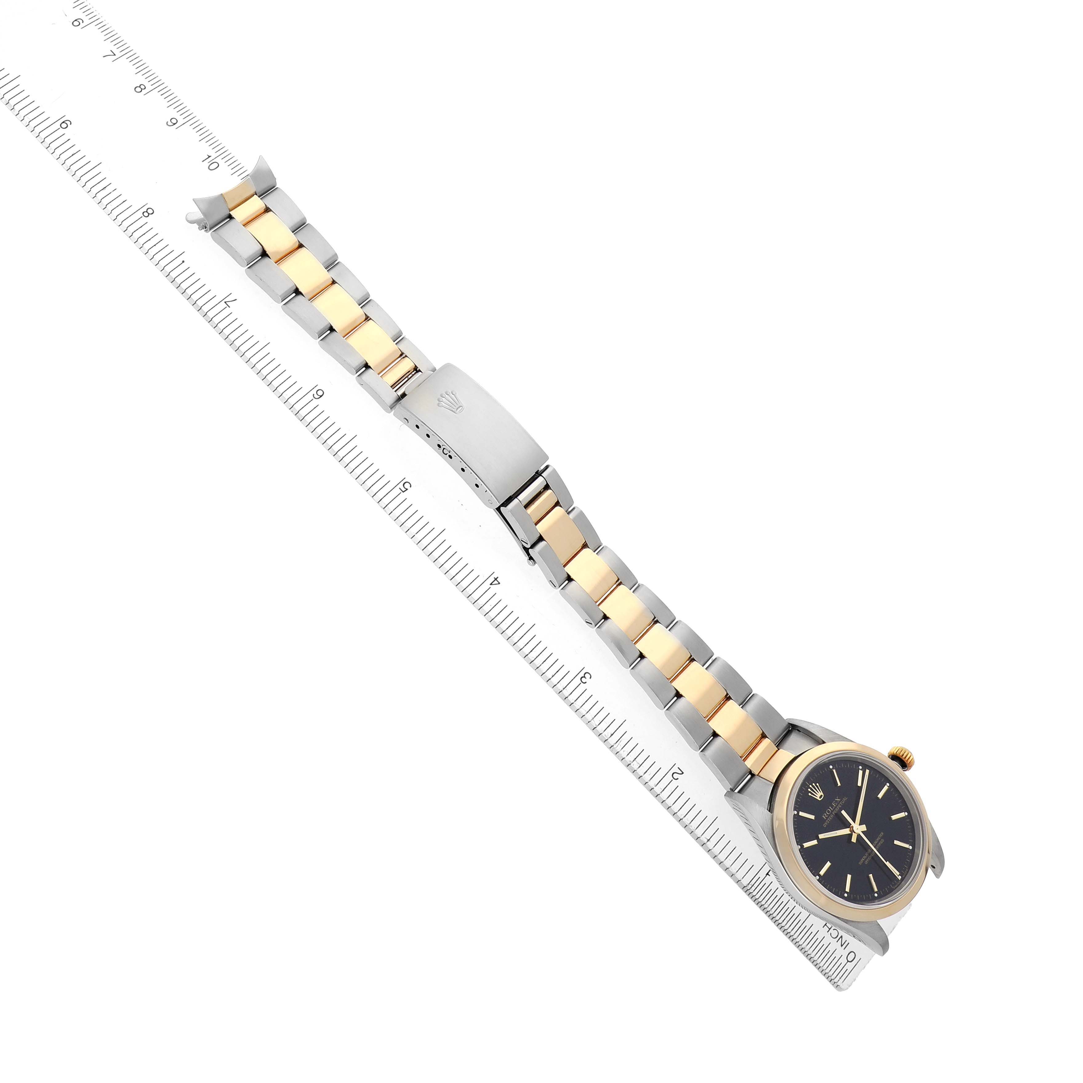 The Rolex Oyster Perpetual 14203 Men's Steel and Gold (two tone) Black Dial watch is shown at an angle displaying the full bracelet alongside a ruler.