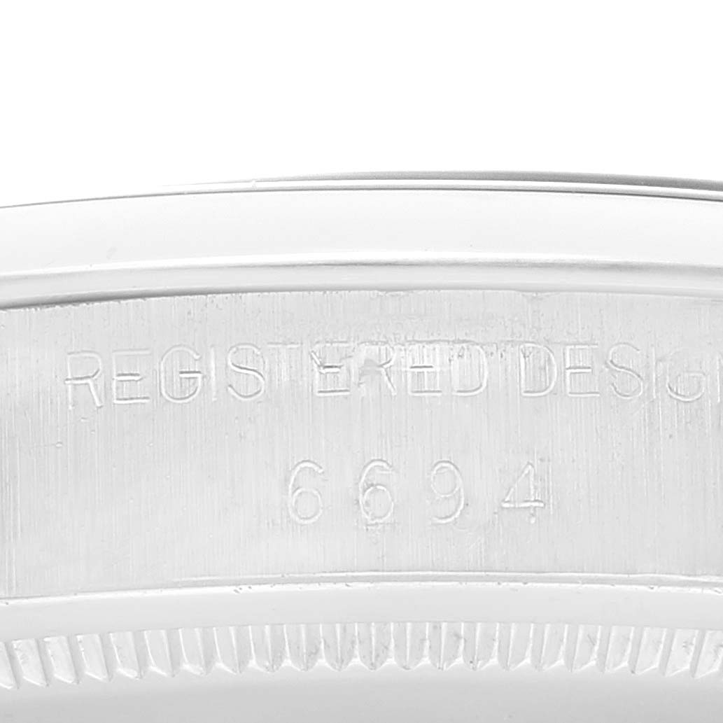 The image shows a close-up of the side of a Rolex Vintage Collection 6694 Men's Stainless Steel Black Dial 6694 Men's Stainless Steel Black Dial watch, highlighting the engraved "REGISTERED DESIGN" and model number 6694.
