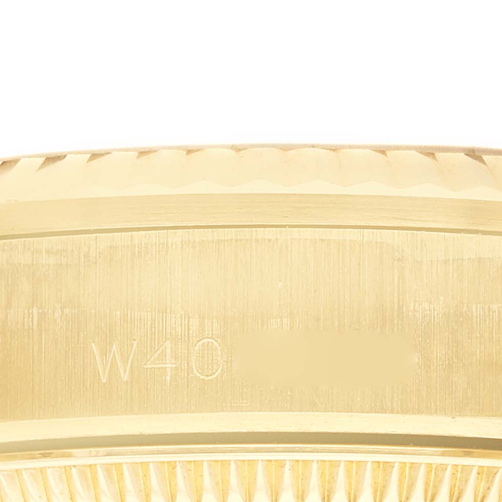 The image shows a close-up side angle of a gold Rolex President 68278 Women's Yellow Gold Silver Dial watch bezel and engraved details.