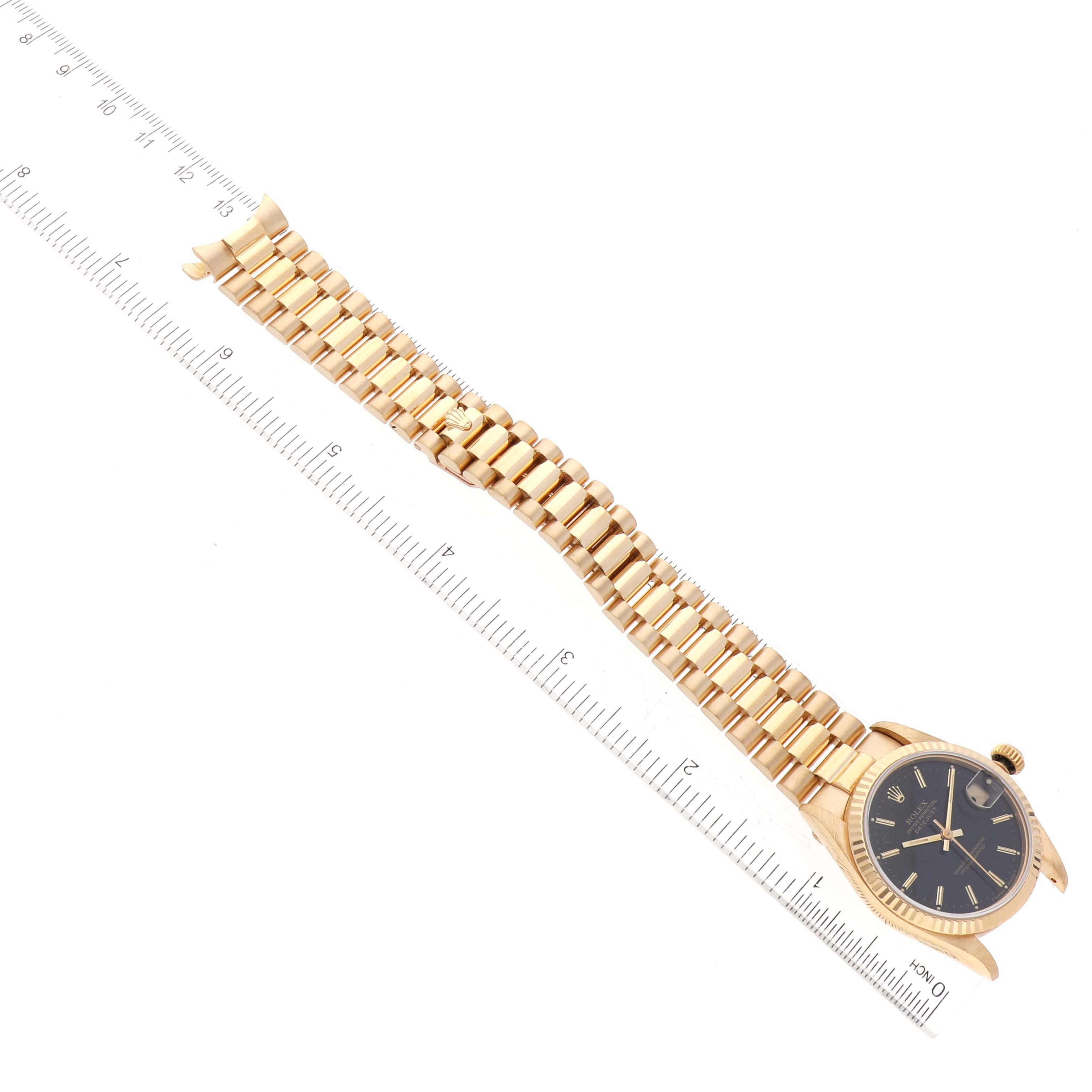 The image shows the Rolex President 68278 Women's Yellow Gold Black Dial 68278 Women's Yellow Gold Black Dial model watch, featuring its face, bezel, and full bracelet next to a measuring ruler.