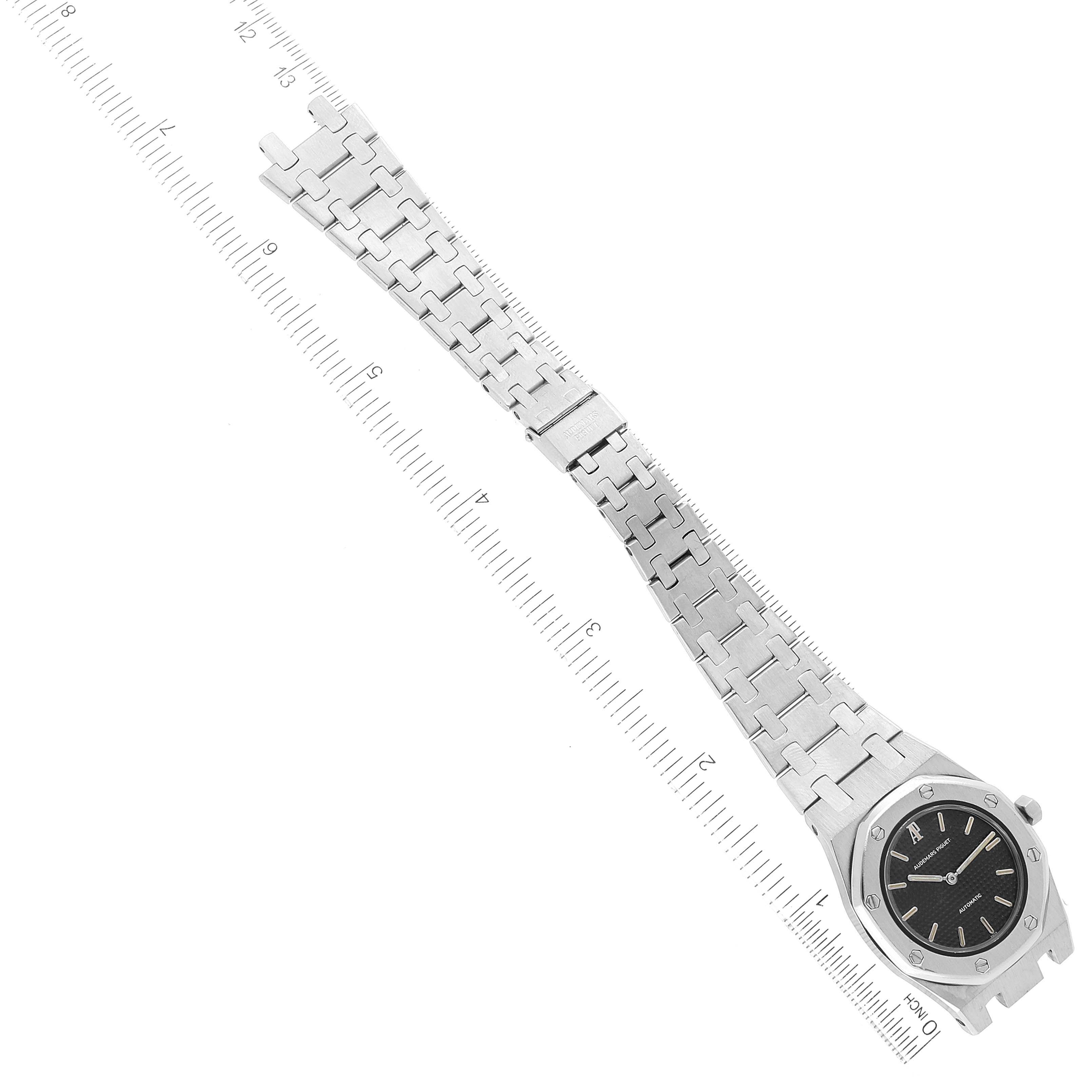 The image shows an Audemars Piguet Royal Oak Women's Stainless Steel Black Dial Women's Stainless Steel Black Dial watch, including its face and metal bracelet, laid flat alongside a ruler for measurement.