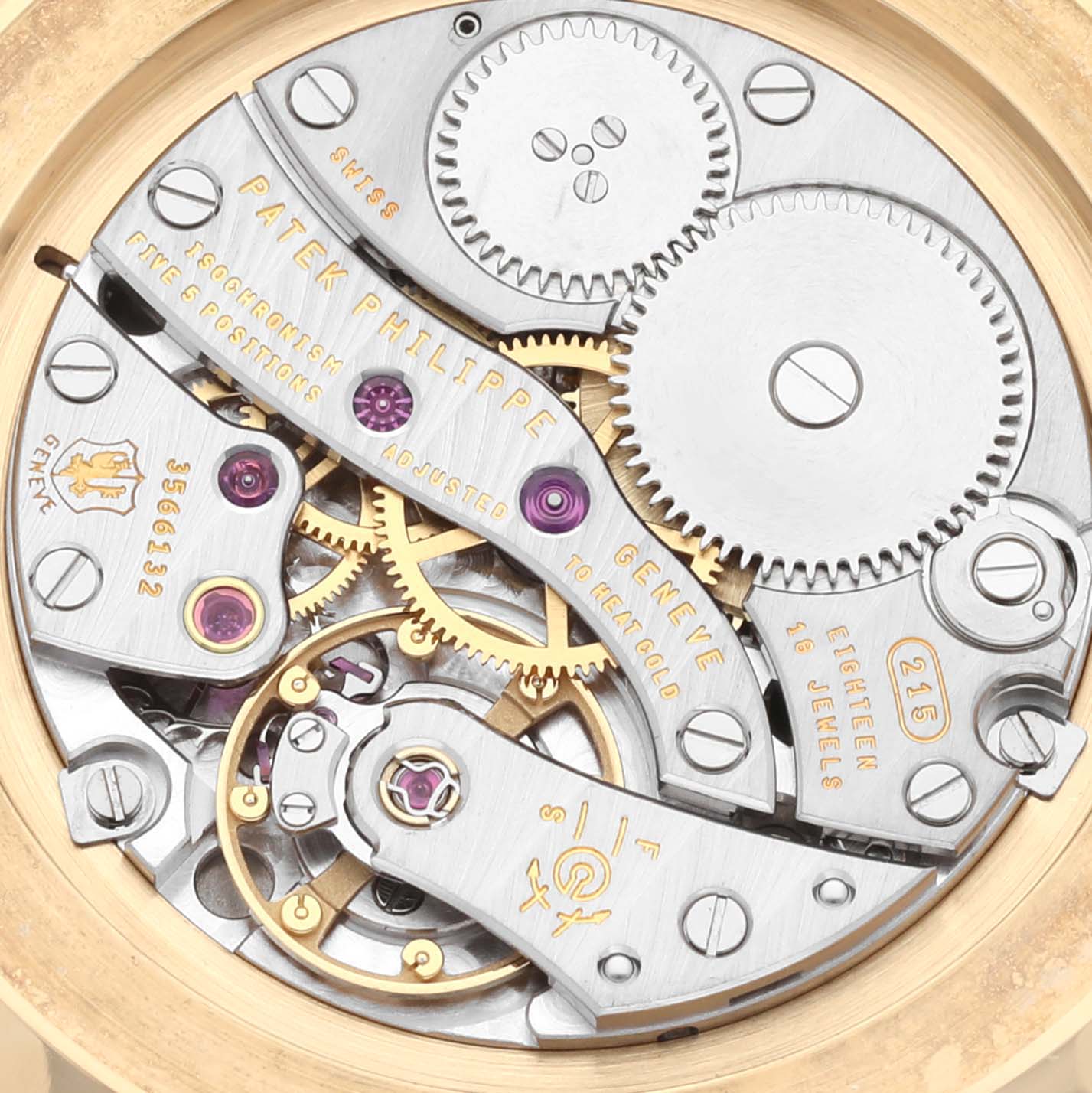 The image shows the intricate movement parts of the Patek Philippe Calatrava 5119J Men's Yellow Gold White Dial 5119J Men's Yellow Gold White Dial watch from a back angle, highlighting gears and jewels.