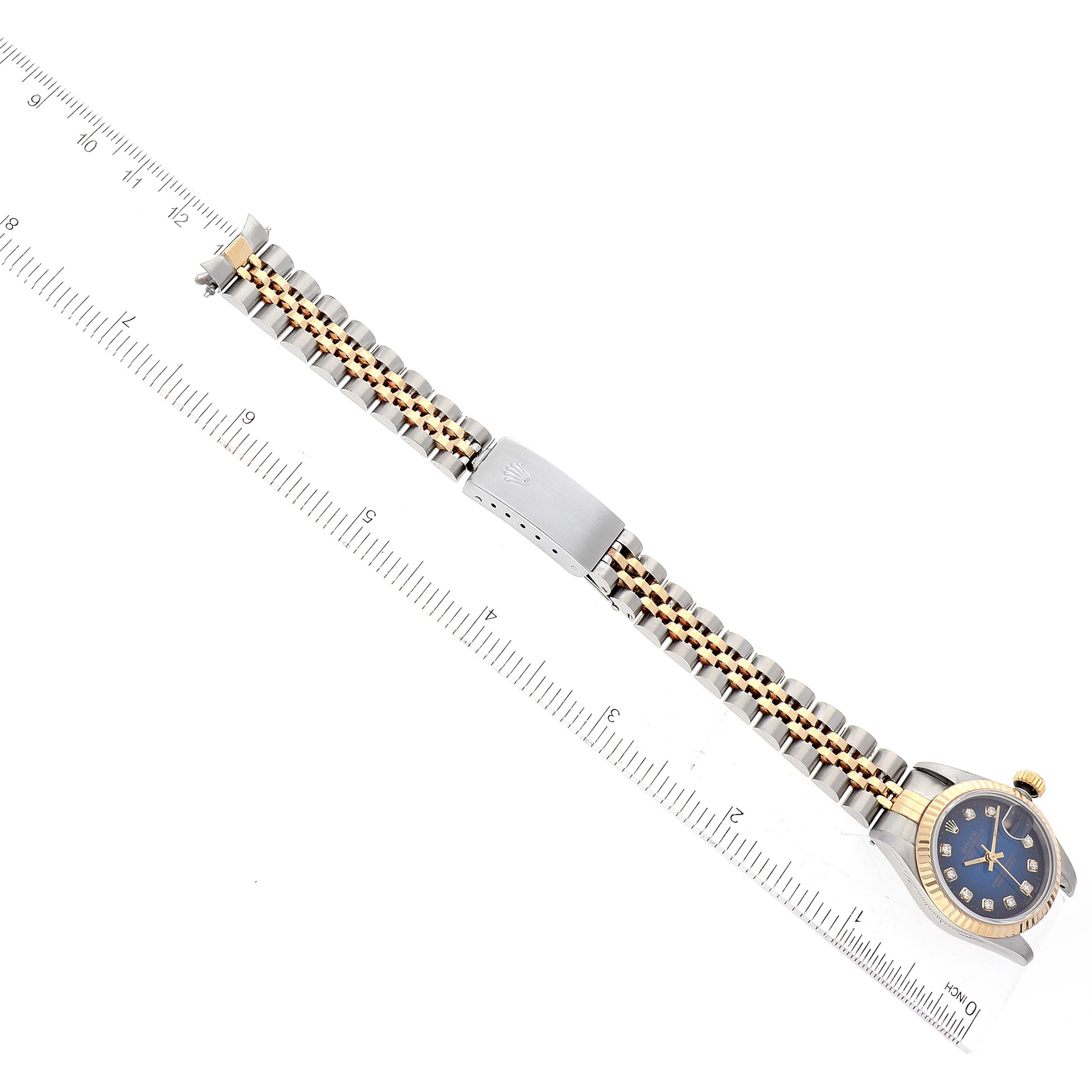 The image shows a full view of the Rolex Datejust 69173 Women's Stainless Steel Blue Dial 69173 Women's Stainless Steel Blue Dial watch with the dial face-up, and the stainless steel and gold bracelet aligned with a ruler.