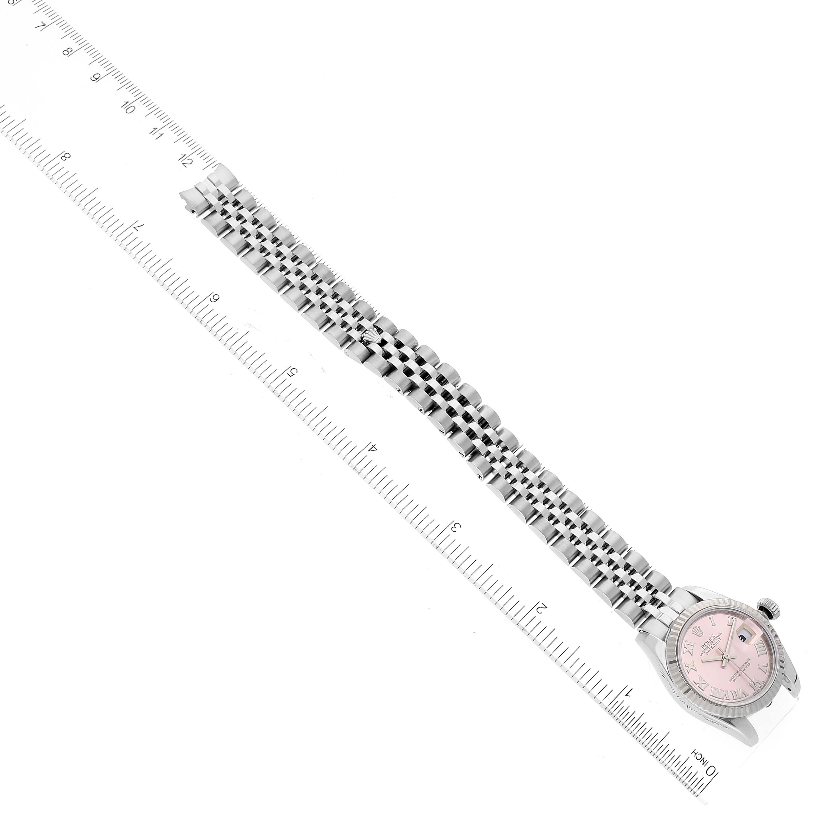 The Rolex Datejust 179174 Women's Stainless Steel Pink Dial 179174 Women's Stainless Steel Pink Dial watch is shown from an overhead angle with its entire band displayed next to a ruler for scale.