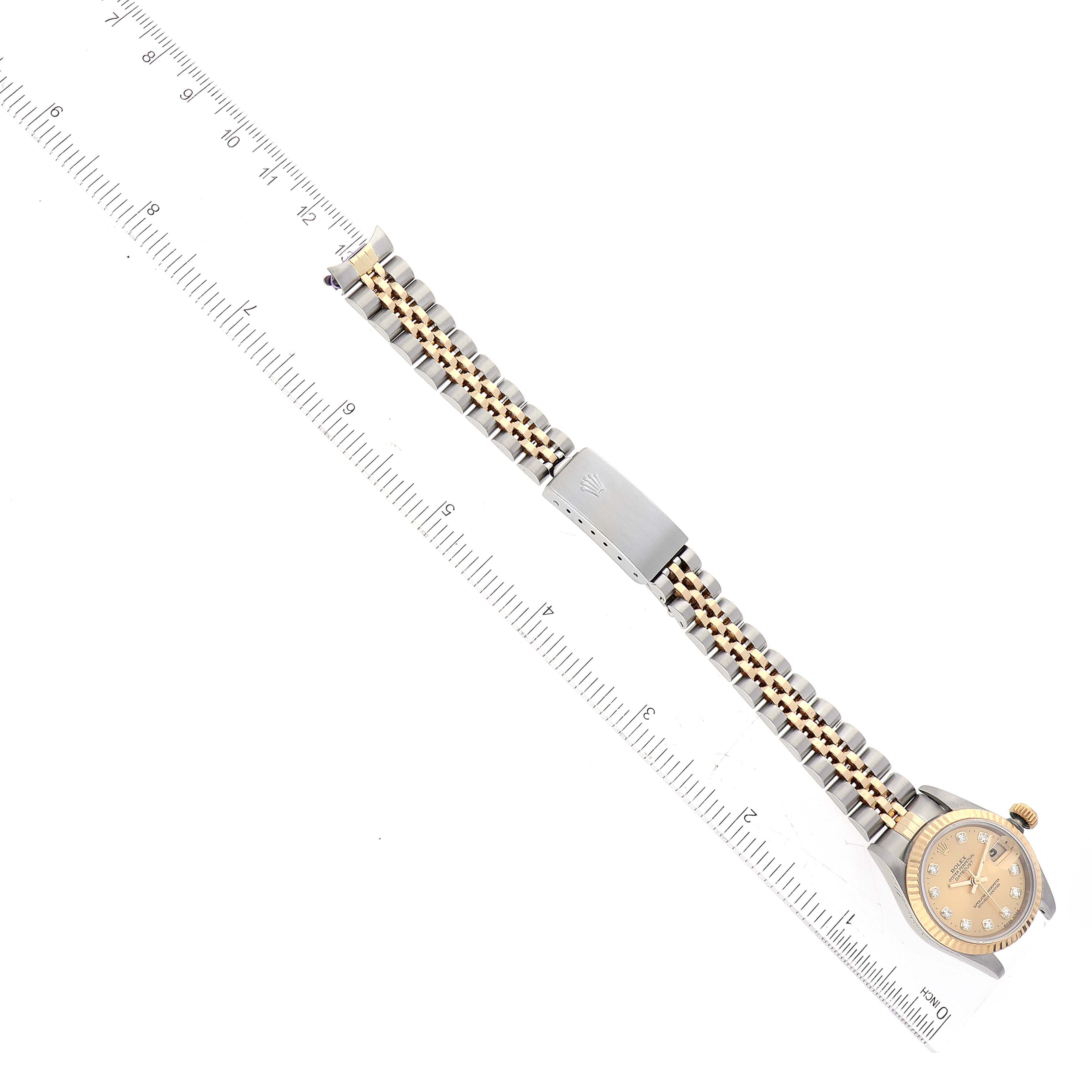The image shows a top-down view of a Rolex Datejust 69173 Women's Steel and Gold (two tone) Champagne Dial 69173 Women's Steel and Gold (two tone) Champagne Dial watch with its full band aligned beside a ruler.