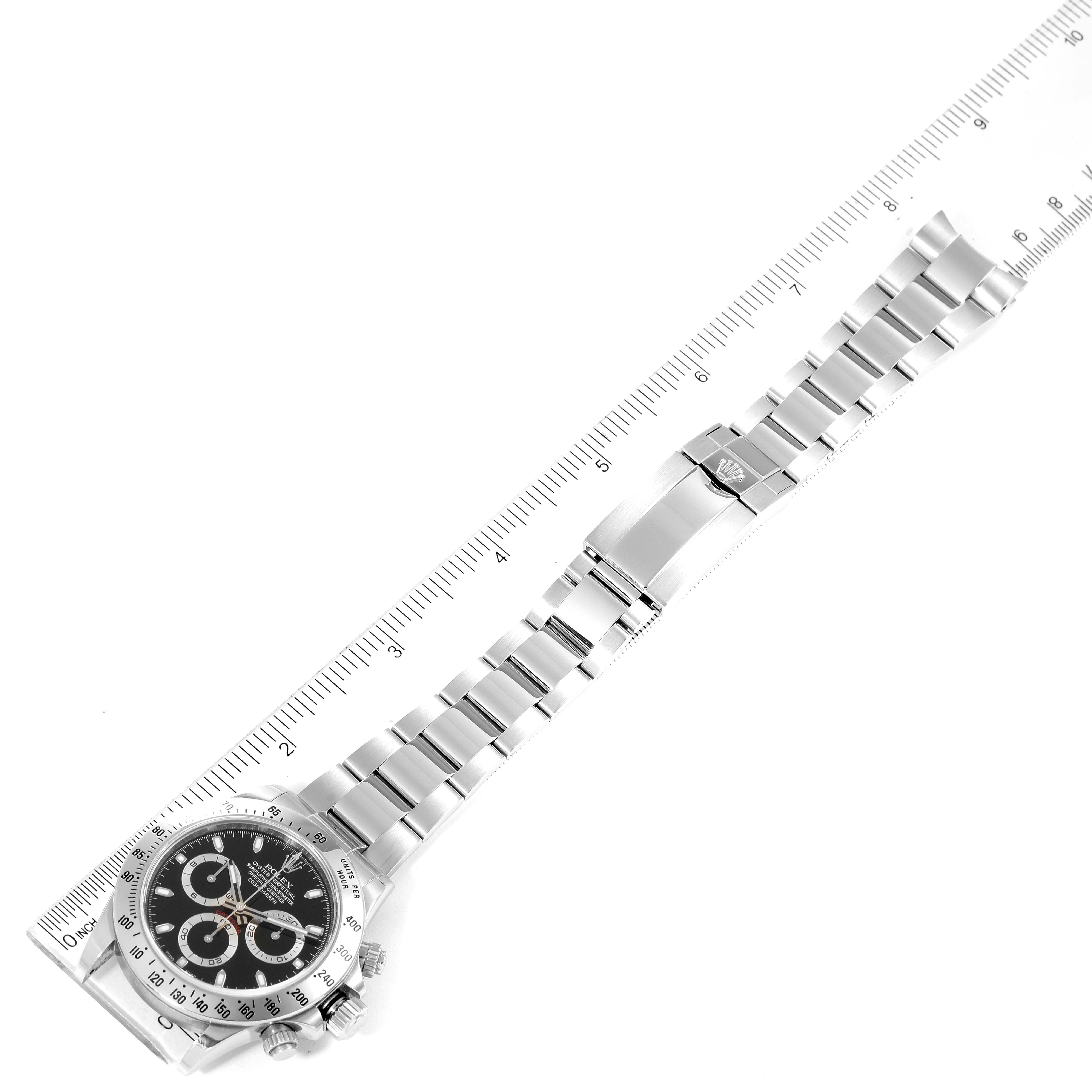 The image shows a top-down view of a Rolex Daytona 116520 Men
s Stainless Steel Black Dial 116520 Men
s Stainless Steel Black Dial watch with a ruler alongside for measurement.