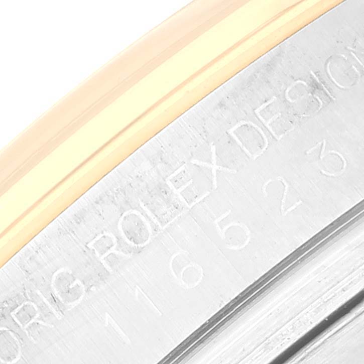 This close-up image shows the engraved serial number and "ROLEX DESIGN" inscription on the case back rim of a Rolex Daytona 116523 Men's Steel and Gold (two tone) Blue Dial 116523 Men's Steel and Gold (two tone) Blue Dial watch.