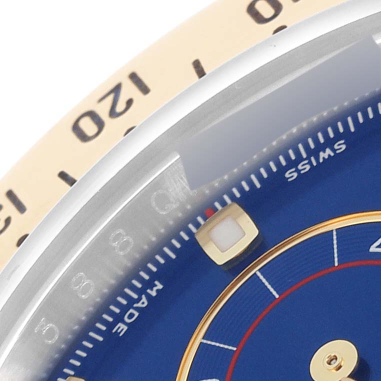 This close-up angle of the Rolex Daytona 116523 Men's Steel and Gold (two tone) Blue Dial 116523 Men's Steel and Gold (two tone) Blue Dial watch shows part of the bezel, dial, and hour markers.