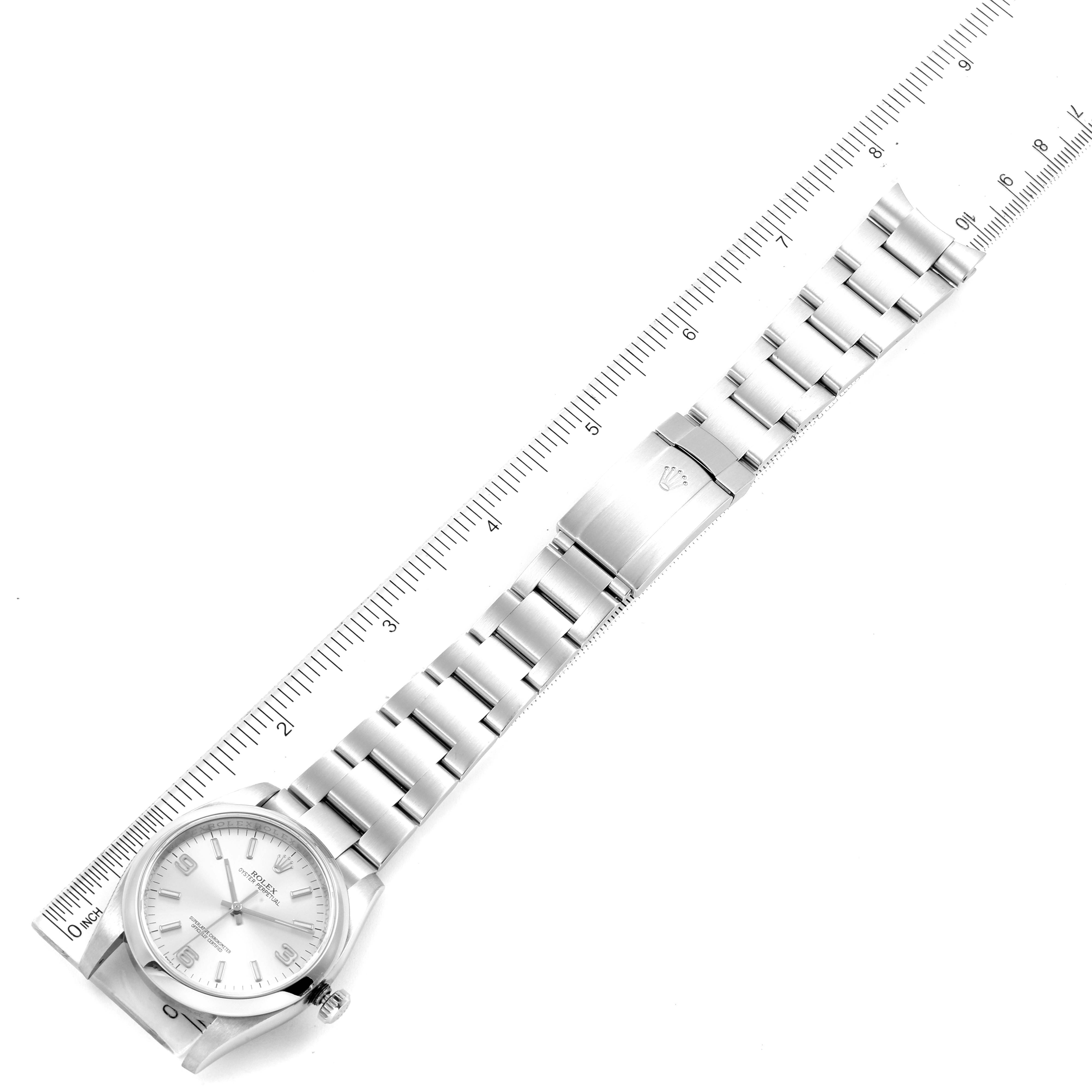 The Rolex Oyster Perpetual 116000 Men's Stainless Steel Silver Dial 116000 Men's Stainless Steel Silver Dial watch is shown in a flat lay angle with a ruler measuring its length.