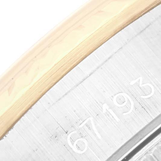 This close-up view of a Rolex Oyster Perpetual 67193 Women's Steel and Gold (two tone) White Dial 67193 Women's Steel and Gold (two tone) White Dial watch shows part of the case with engraved numbers.