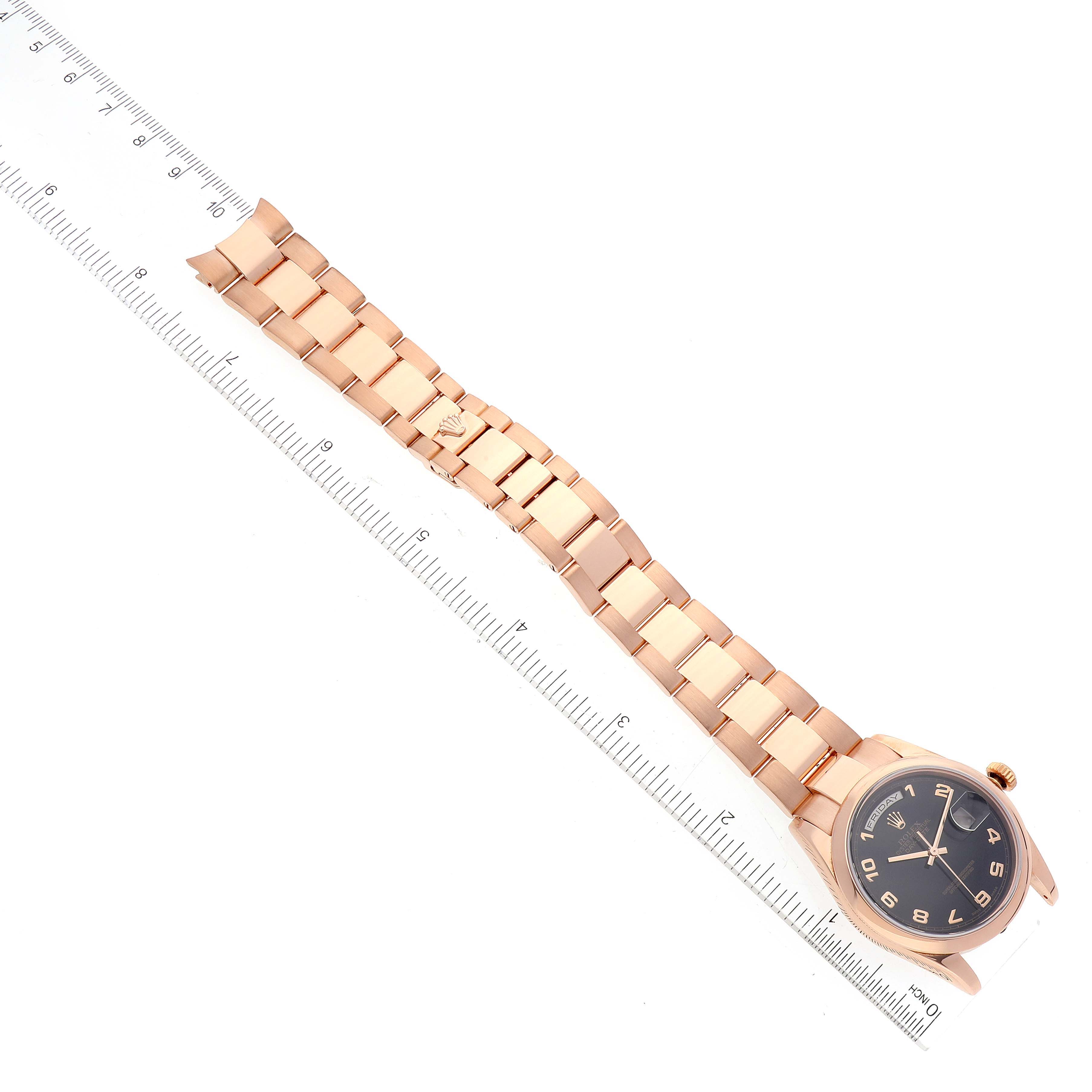 This image shows the Rolex President 118205 Men
s Rose Gold Black Dial 118205 Men
s Rose Gold Black Dial model watch from an overhead angle, highlighting the bracelet and face alongside a ruler for scale.