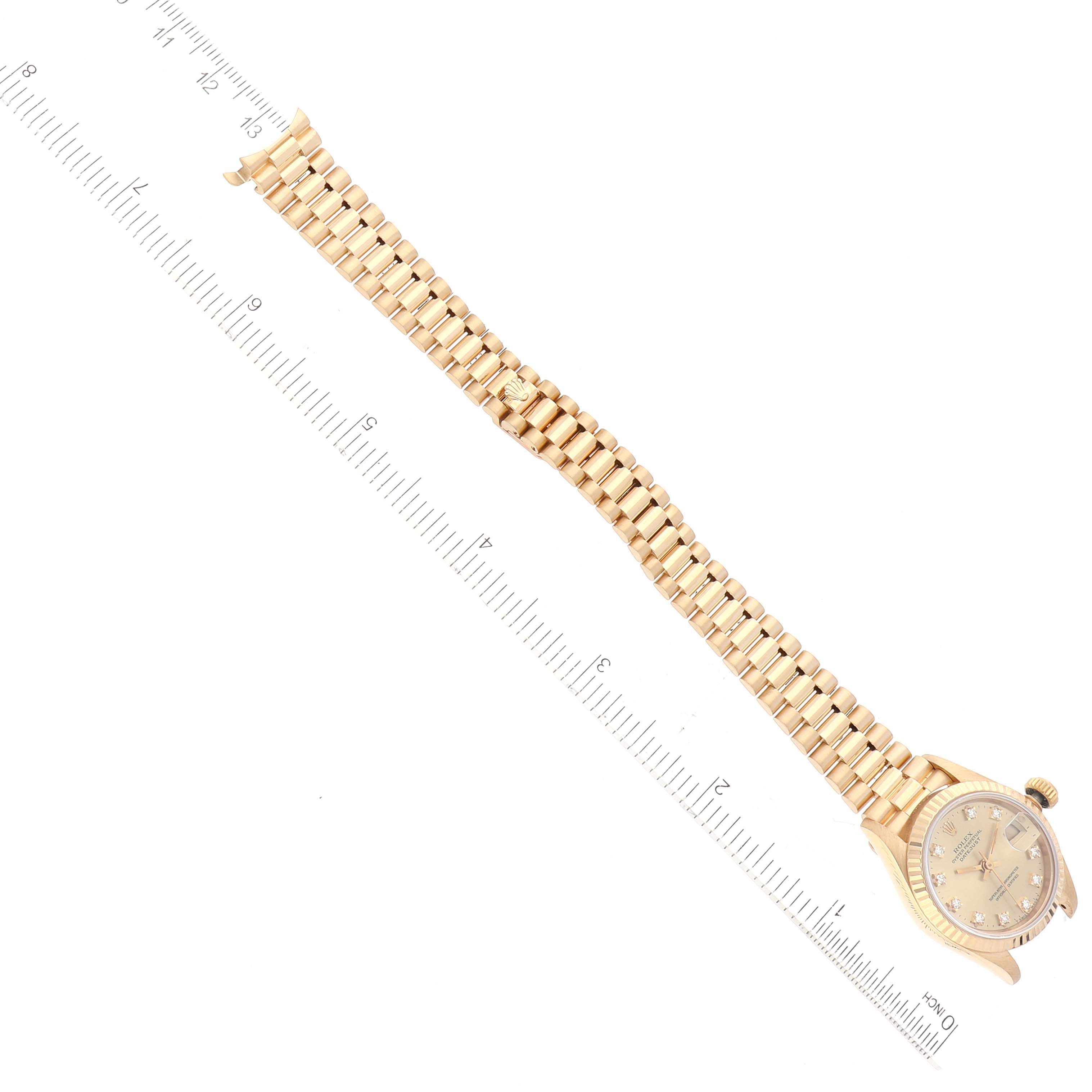 The image shows a top-down view of a Rolex President 69178 Women's Yellow Gold Champagne Dial 69178 Women's Yellow Gold Champagne Dial model watch displaying its case, dial, and full bracelet beside a ruler.