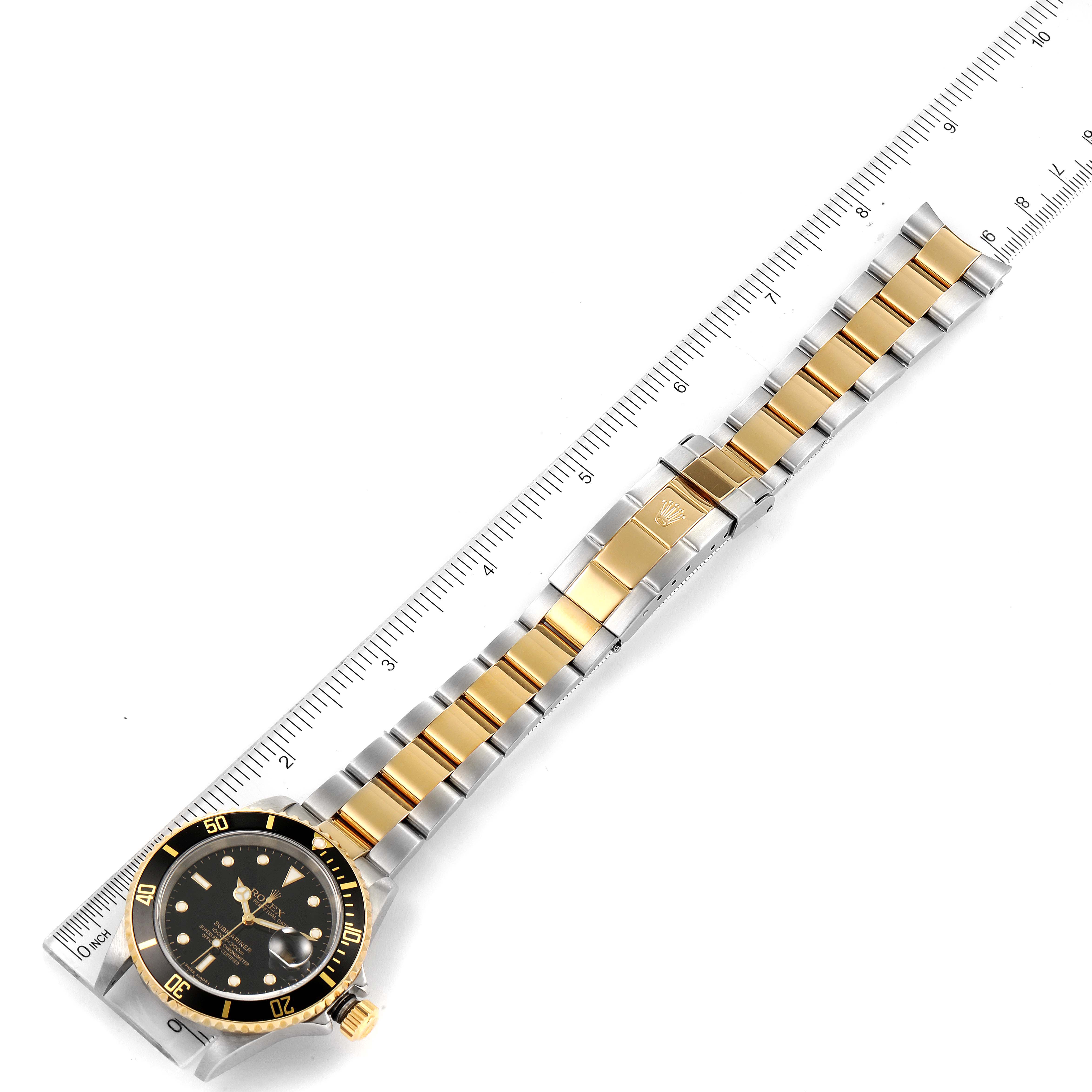 This image shows a top view of a Rolex Submariner 16613 Men's Steel and Gold (two tone) Black Dial 16613 Men's Steel and Gold (two tone) Black Dial watch, displaying its dial, bezel, and two-tone metal bracelet beside a ruler.
