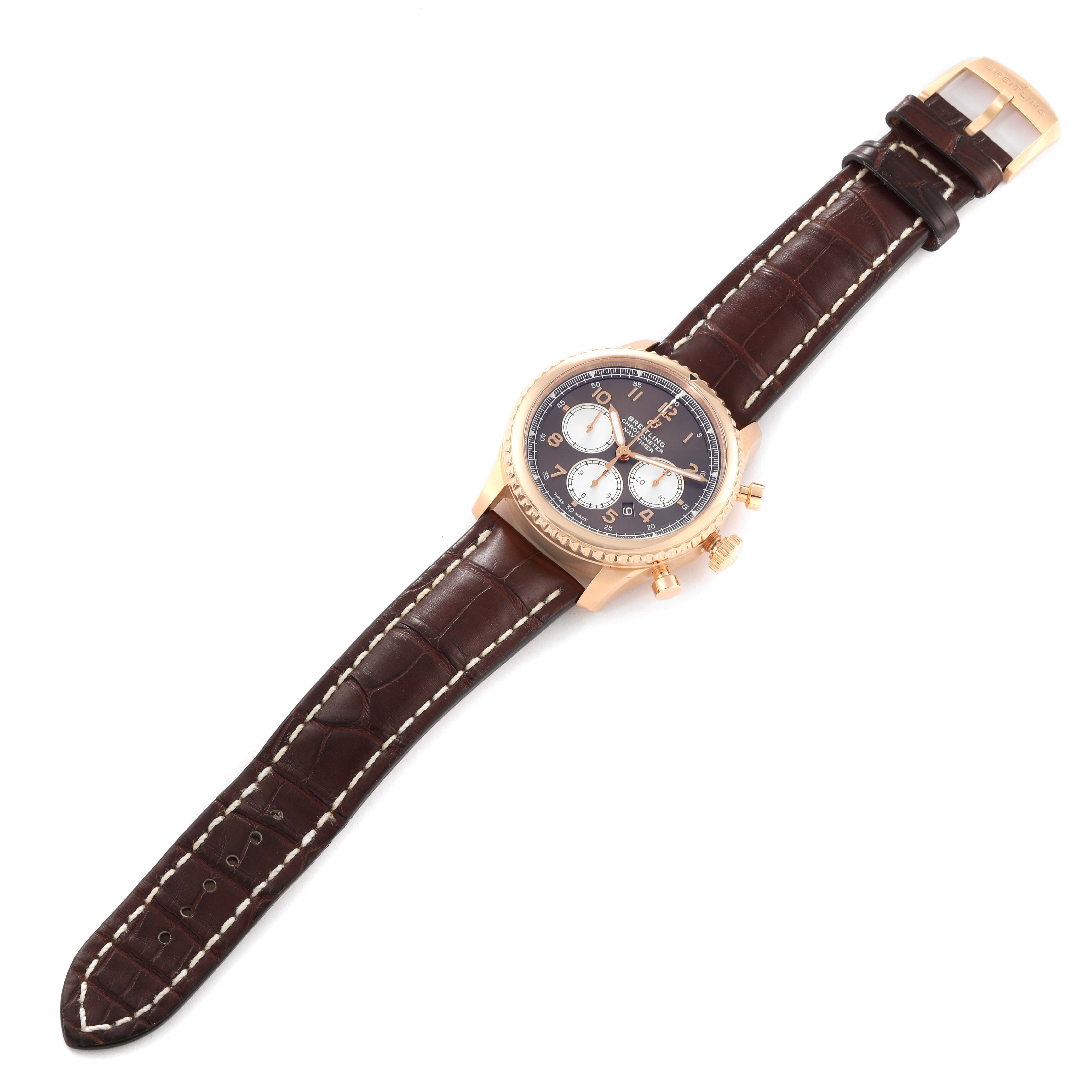 The Breitling Navitimer watch is shown from a top-down angle, displaying its face, bezel, and brown leather strap. 