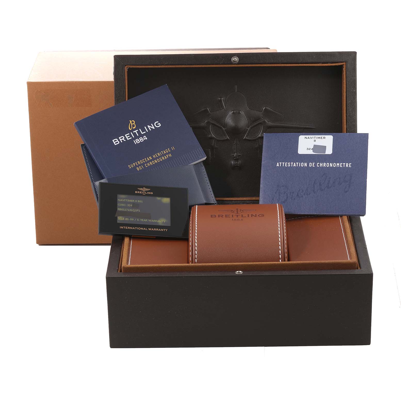 The image shows a Breitling Navitimer watch box containing documentation, warranty card, and a leather case.